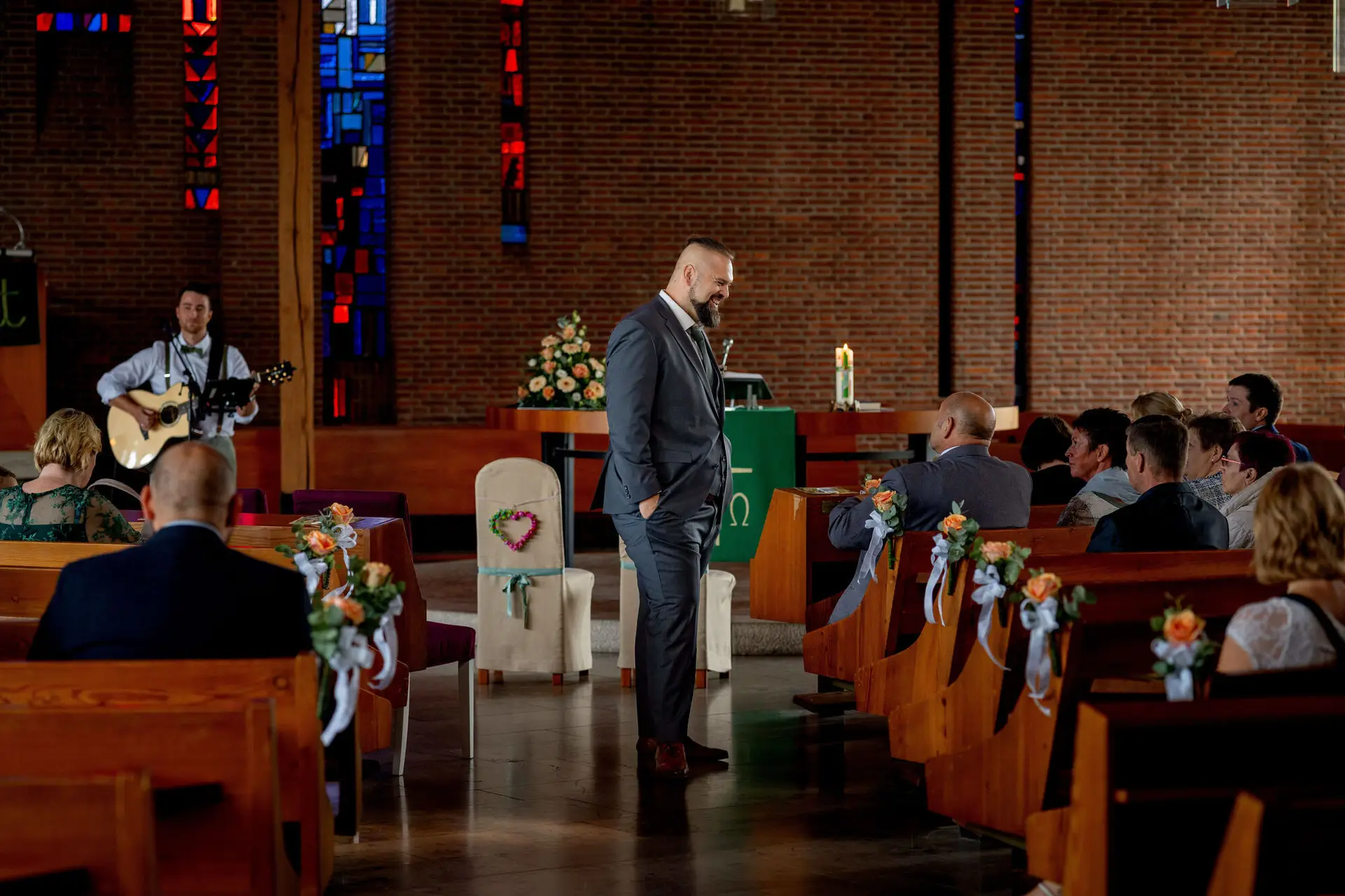 Bräutigam steht am Altar während ein Gitarrist spielt