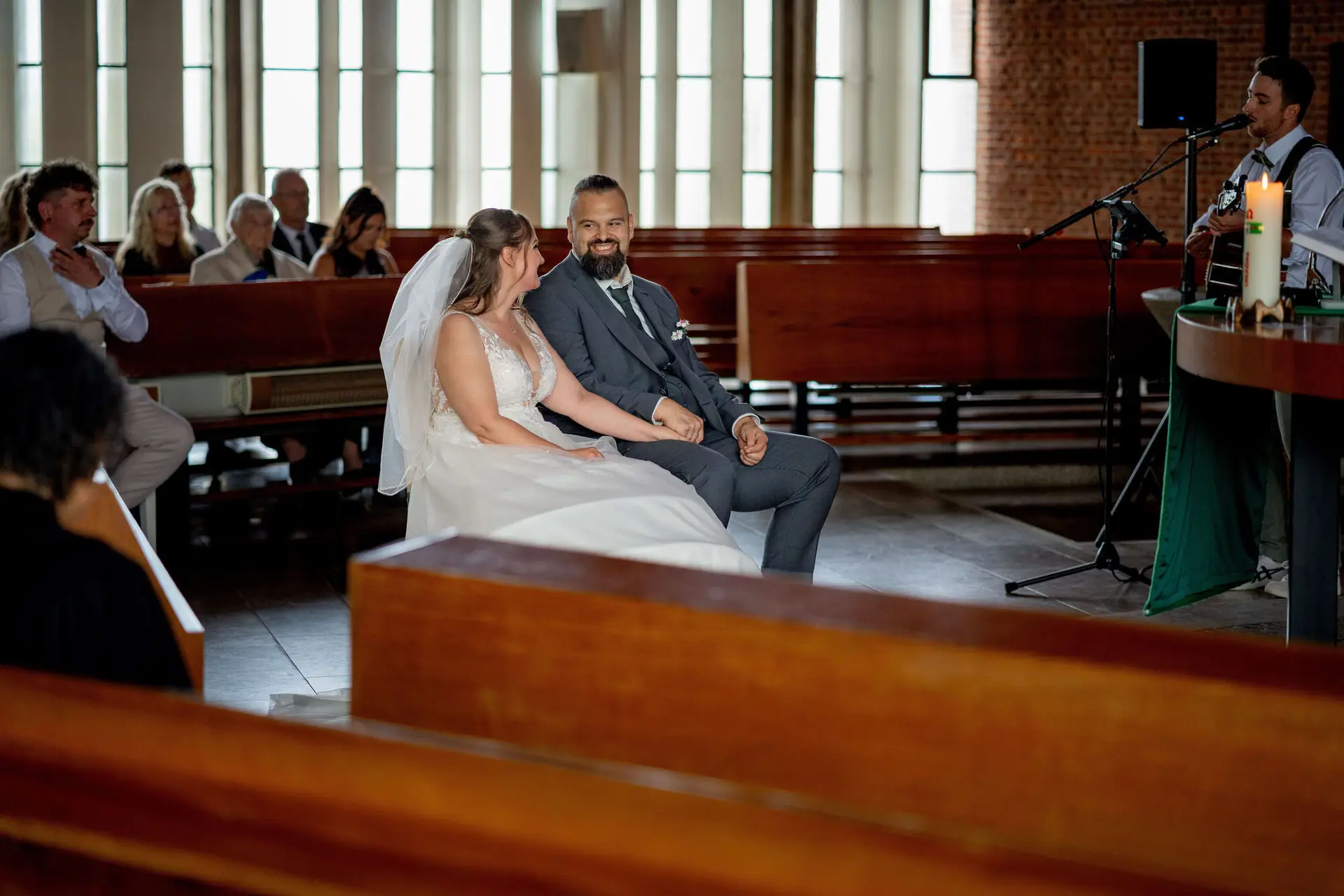 Brautpaar sitzt lächelnd nebeneinander während der Trauung