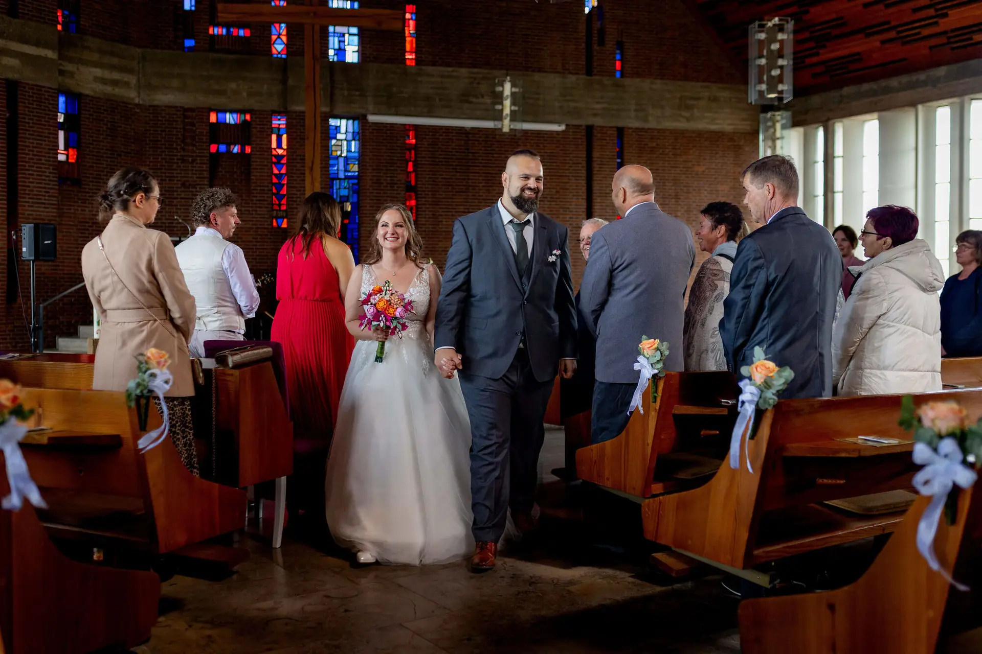 Brautpaar läuft strahlend durch den Mittelgang nach der Trauung