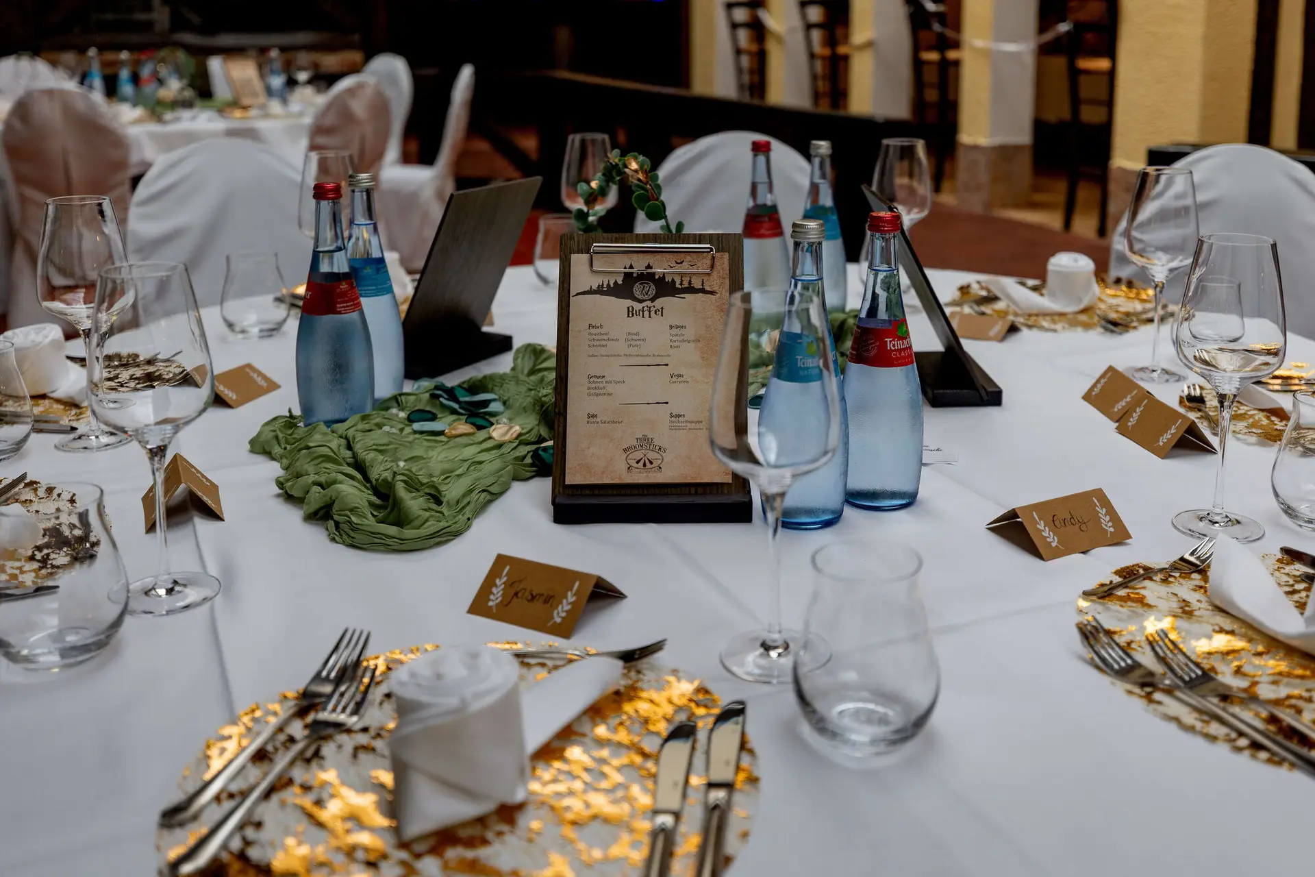Gedeckter Hochzeitstisch mit goldenen Platztellern und Buffet-Karte im Harry-Potter-Stil
