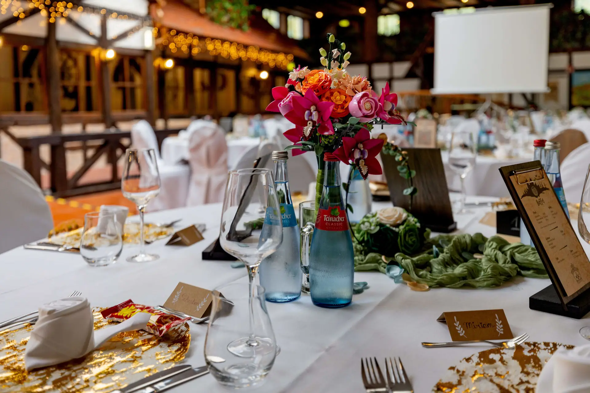 Festlich gedeckte Tafel mit buntem Blumenstrauß und Fachwerk im Hintergrund