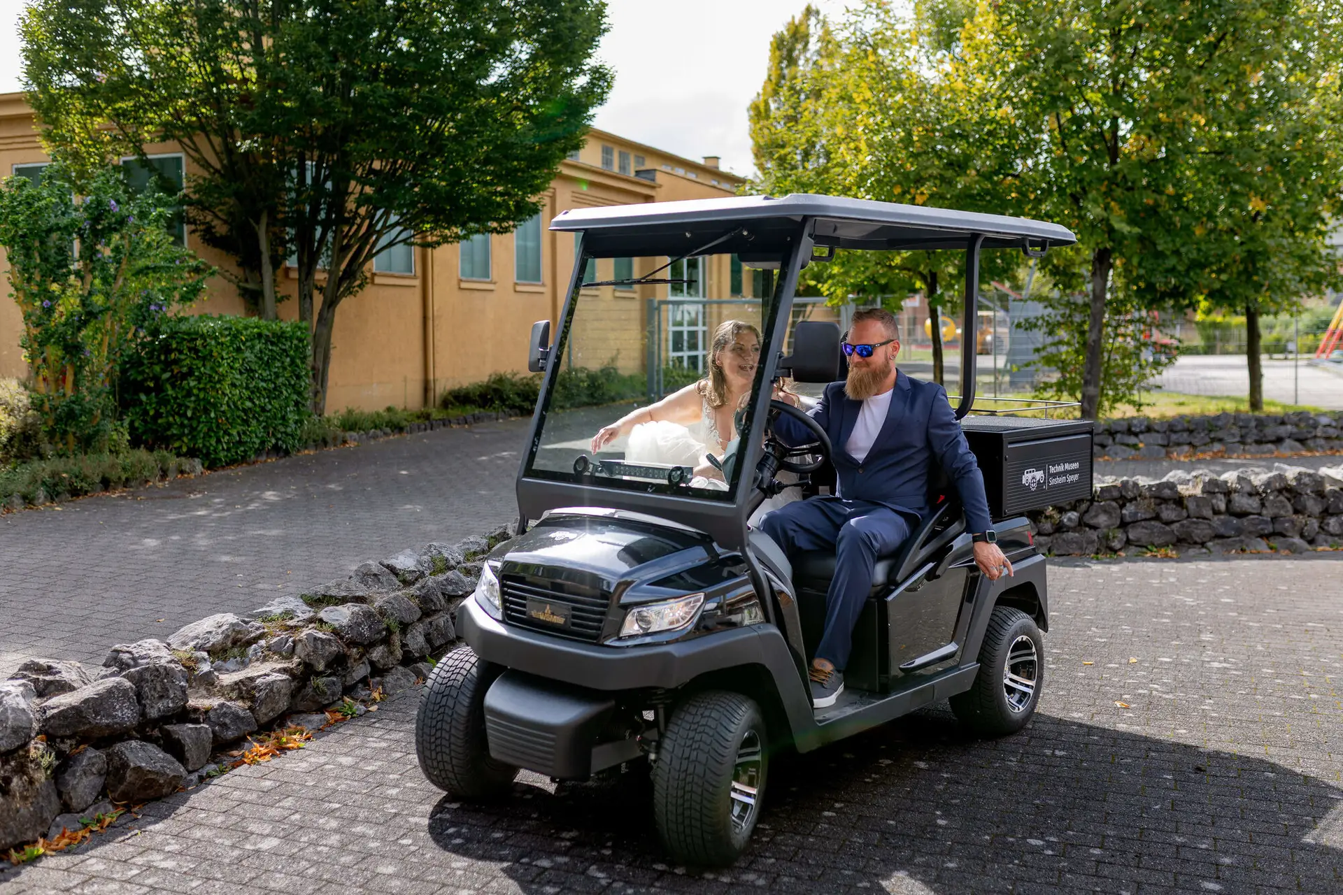 Brautpaar fährt im Golfcart über das Museumsgelände