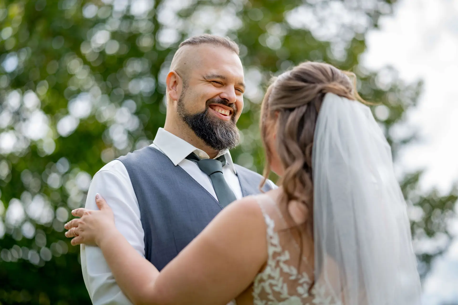 Bräutigam lächelt die Braut an im Grünen