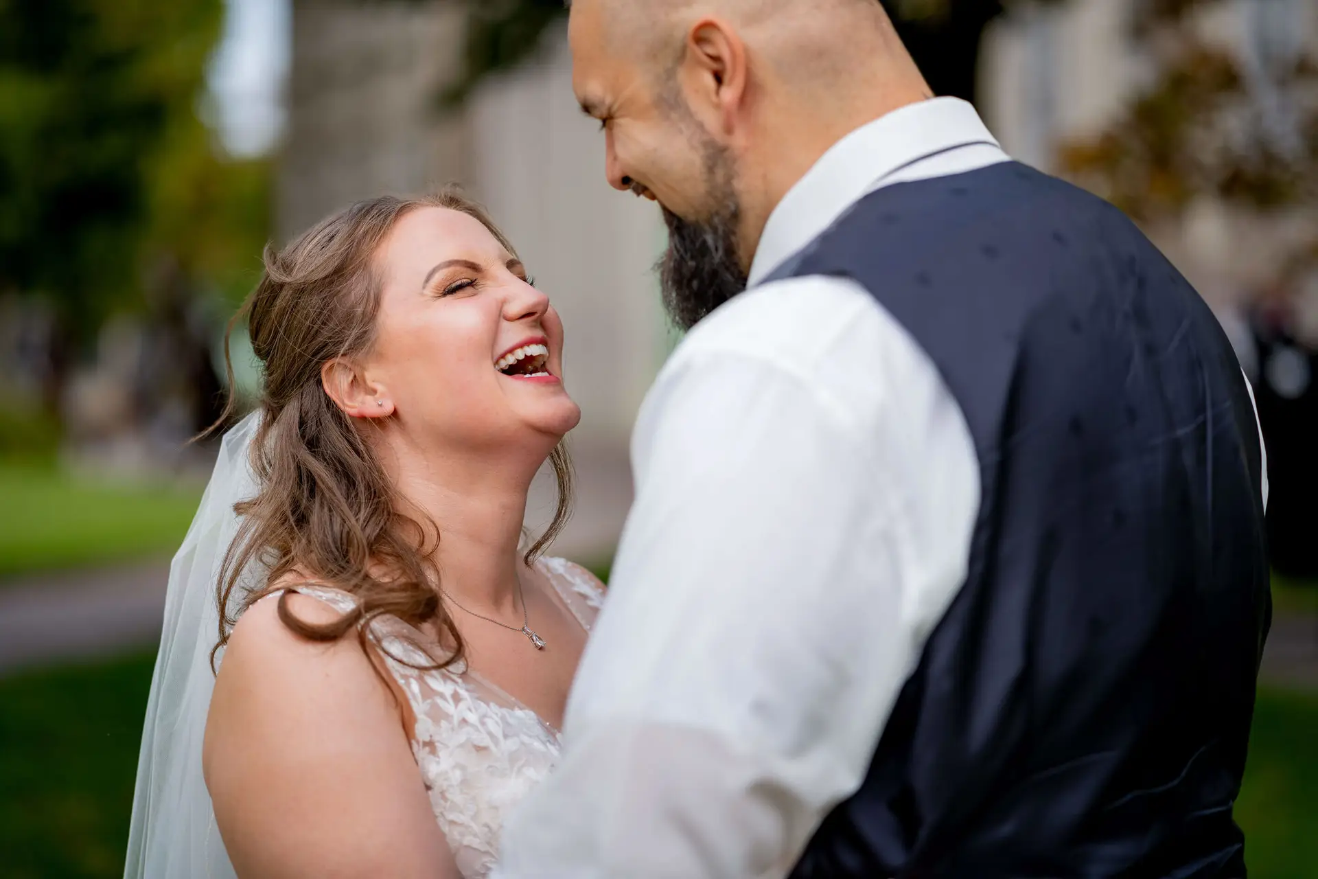 Braut lacht herzlich im Arm des Bräutigams