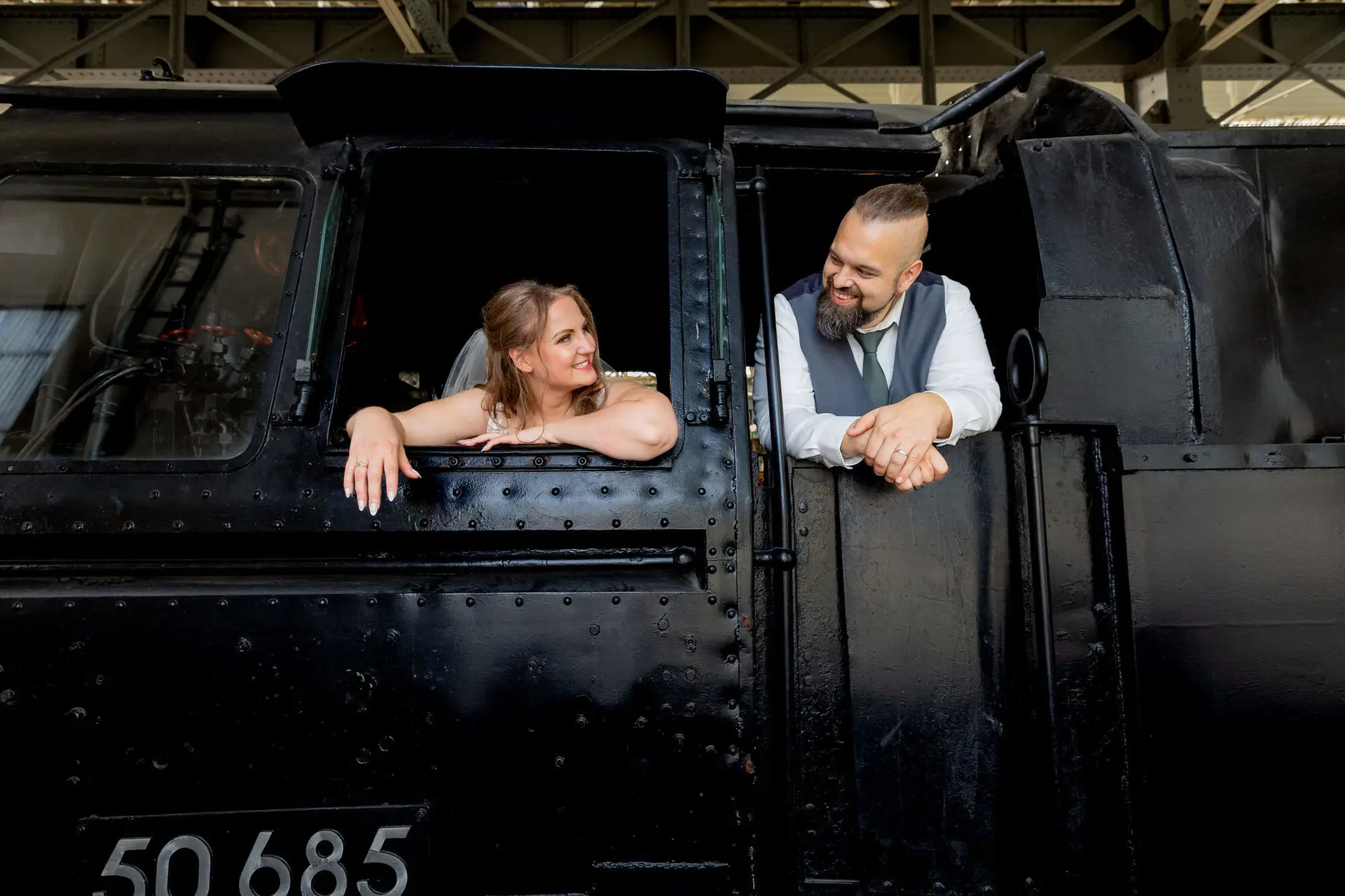 Brautpaar schaut aus dem Führerstand einer Dampflokomotive