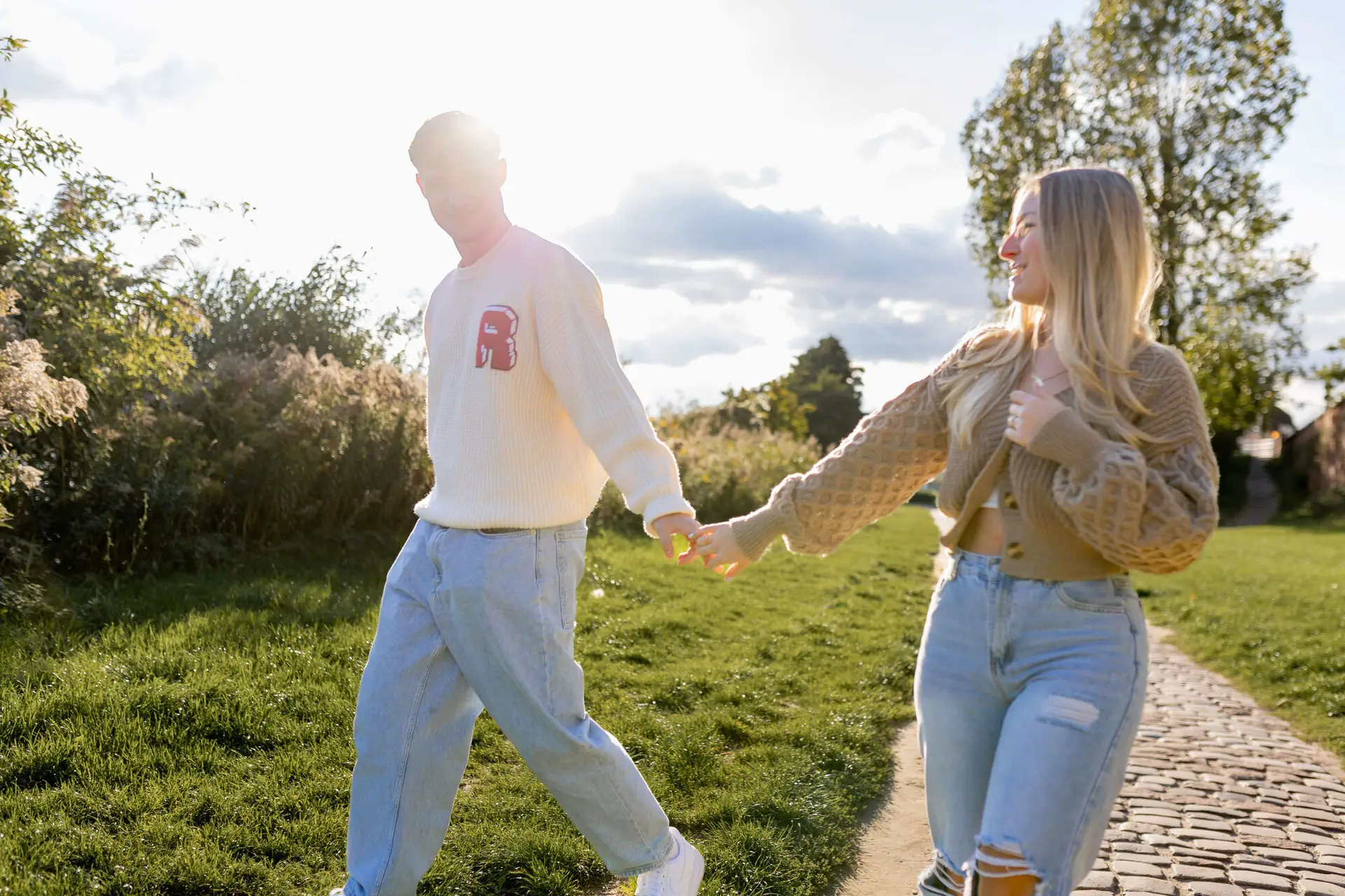 Sebi und Lena laufen Hand in Hand über den Weg an der Neckarwiese, Gegenlicht der tief stehenden Herbstsonne