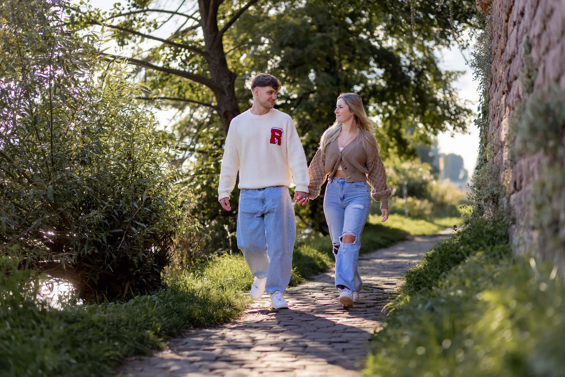 Sebi und Lena spazieren Hand in Hand am Neckarufer in Heidelberg