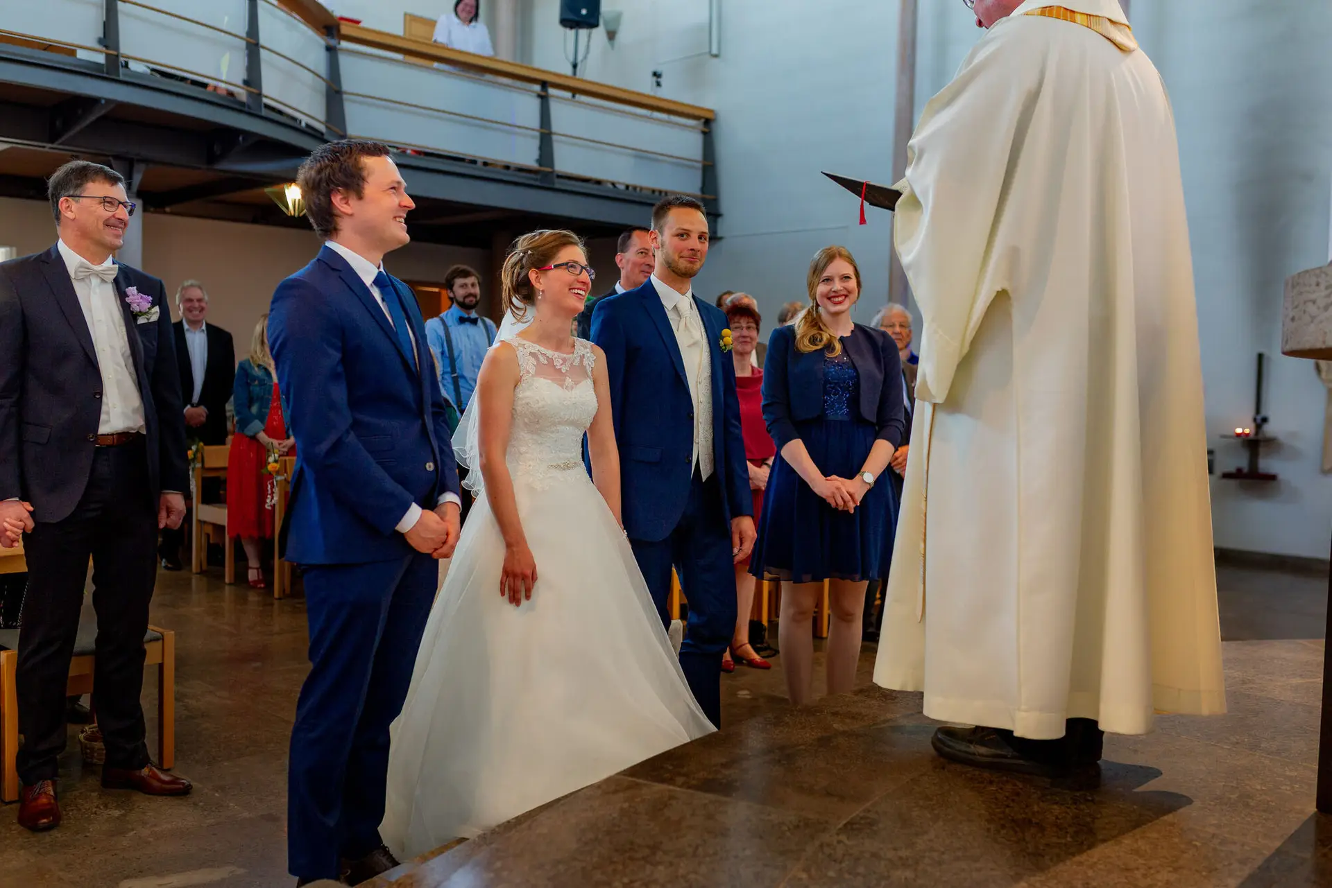 Brautpaar und Trauzeugen lauschen dem Priester während der kirchlichen Trauung im Kirchenschiff