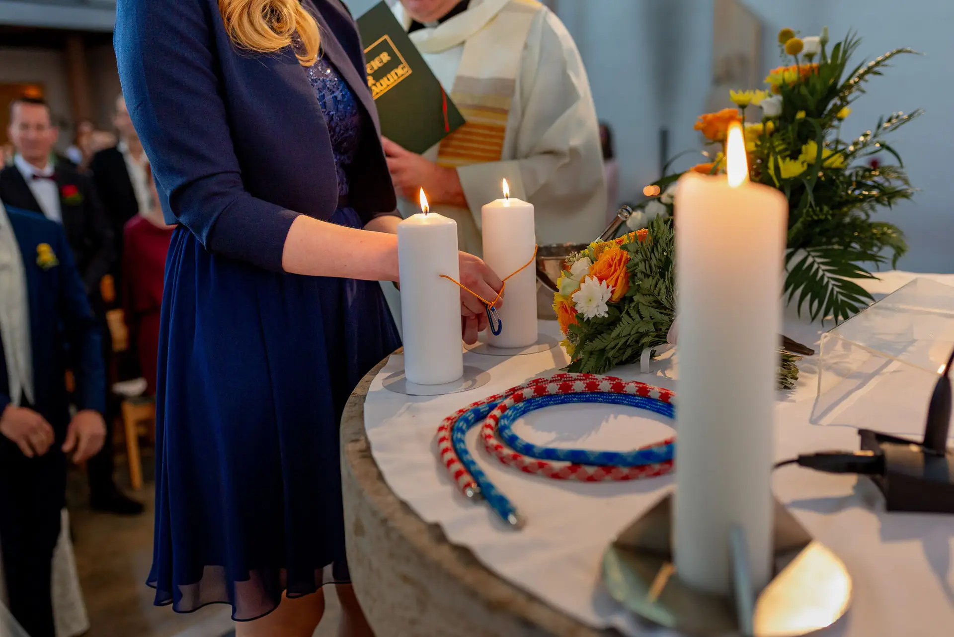 Braut hält feierlich einen Kerzenbinder in der Kirche, Bräutigam steht ihr aufmerksam zur Seite