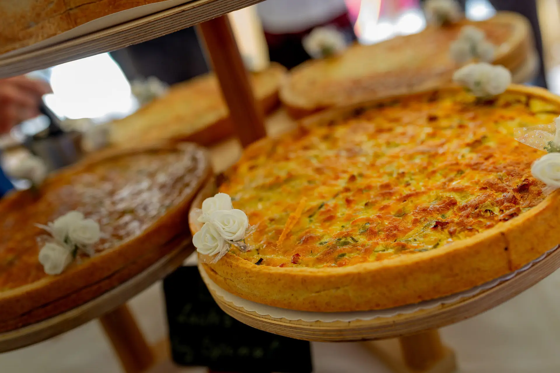 Zwei liebevoll dekorierte Kuchen mit Blumen auf einem Holzgestell, festlicher Hochzeitstisch