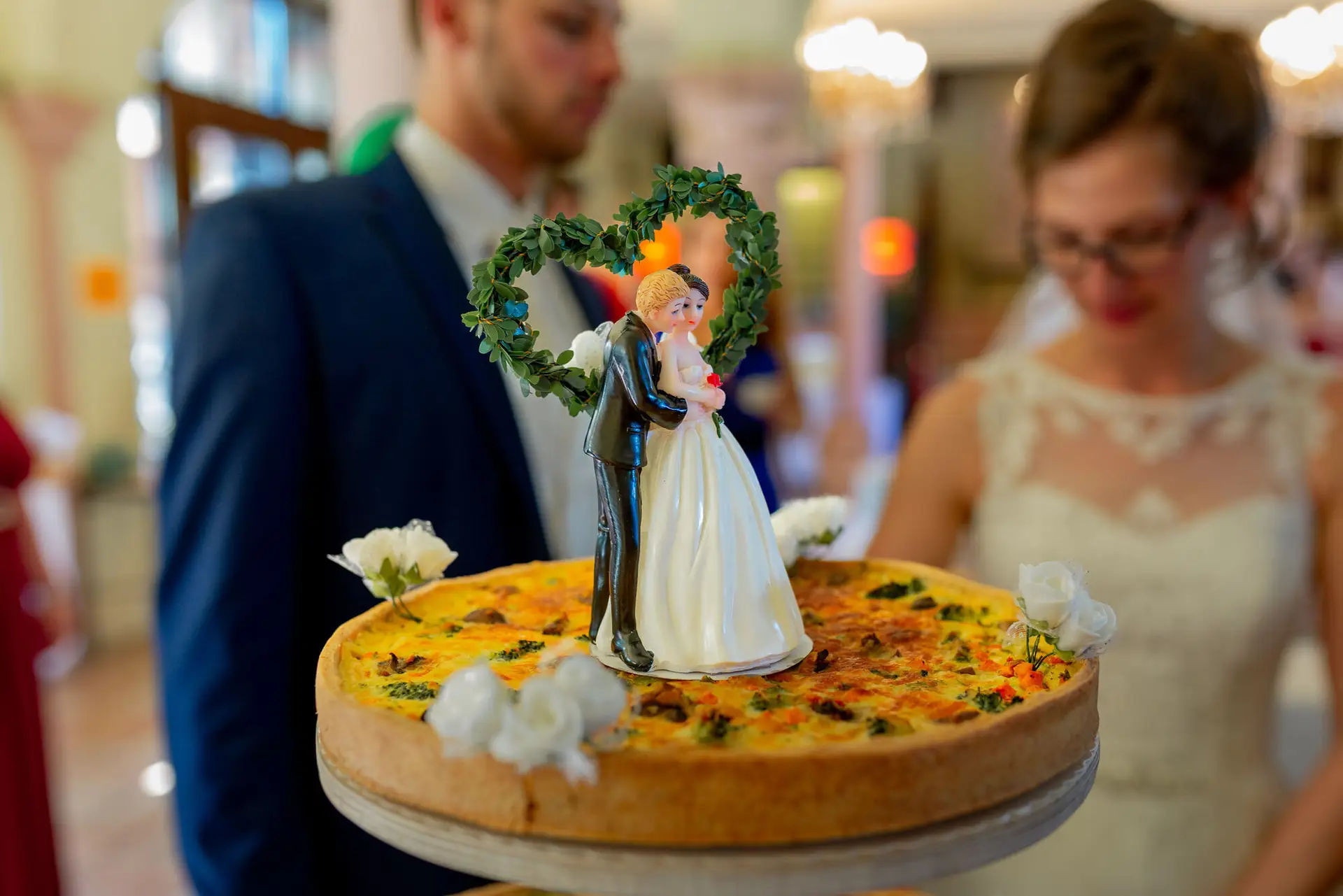 Hochzeitstorte mit kleiner Brautpaar-Figur und weißen Blumendekorationen, elegante Tortengestaltung