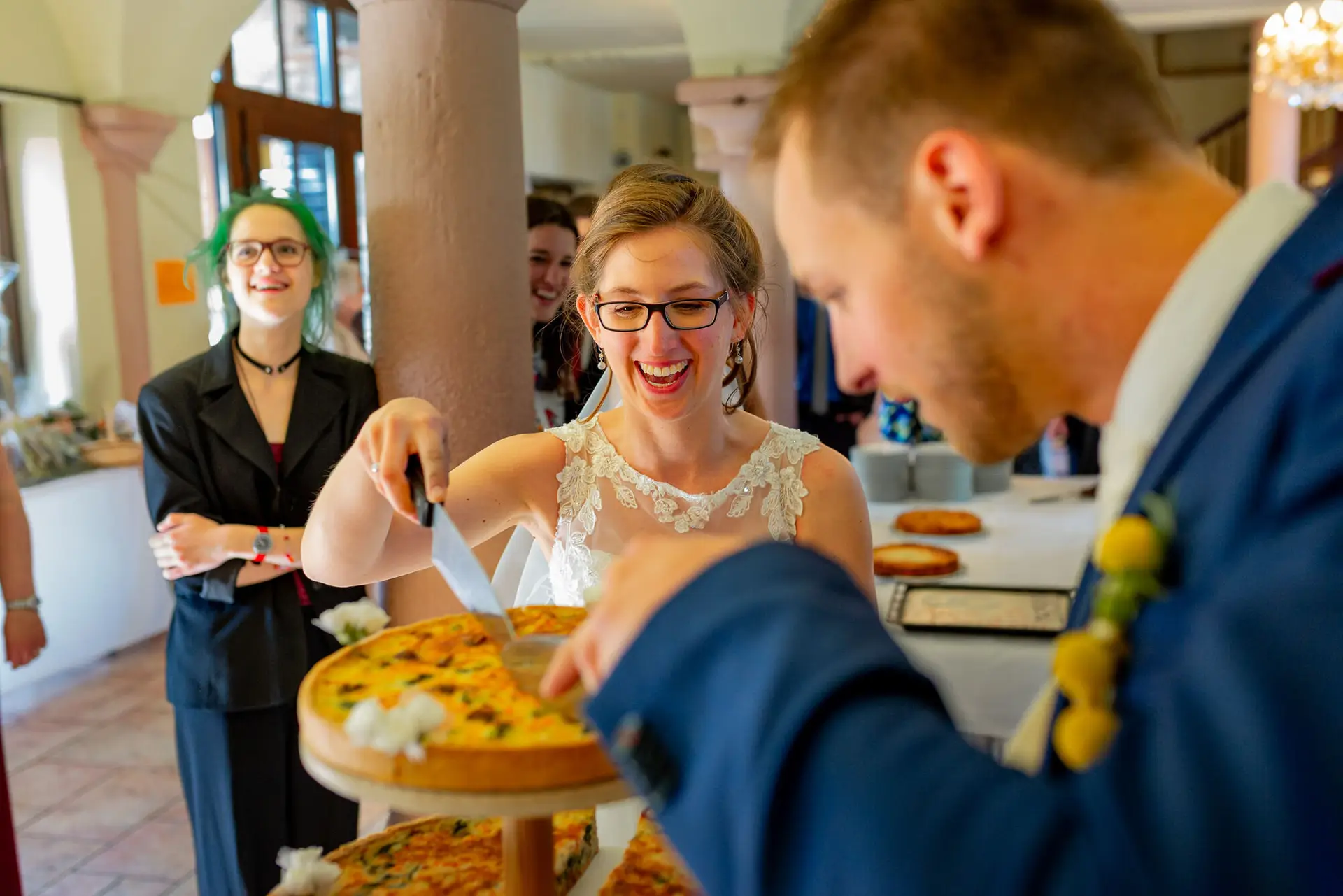 Braut schneidet die Hochzeitstorte feierlich vor den Gästen an