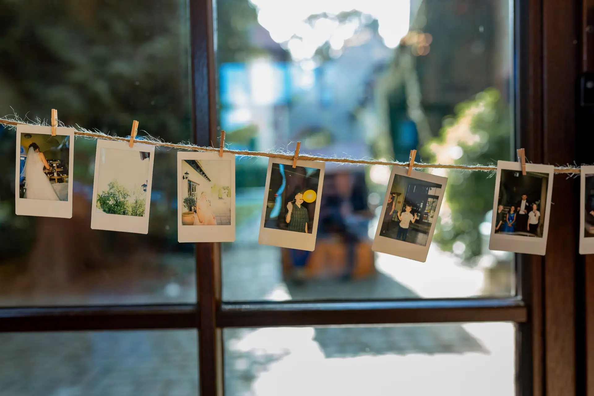 Aufgehängte Polaroid-Fotos des Brautpaares an einer Leine – persönliche Hochzeitsdekoration im Festsaal