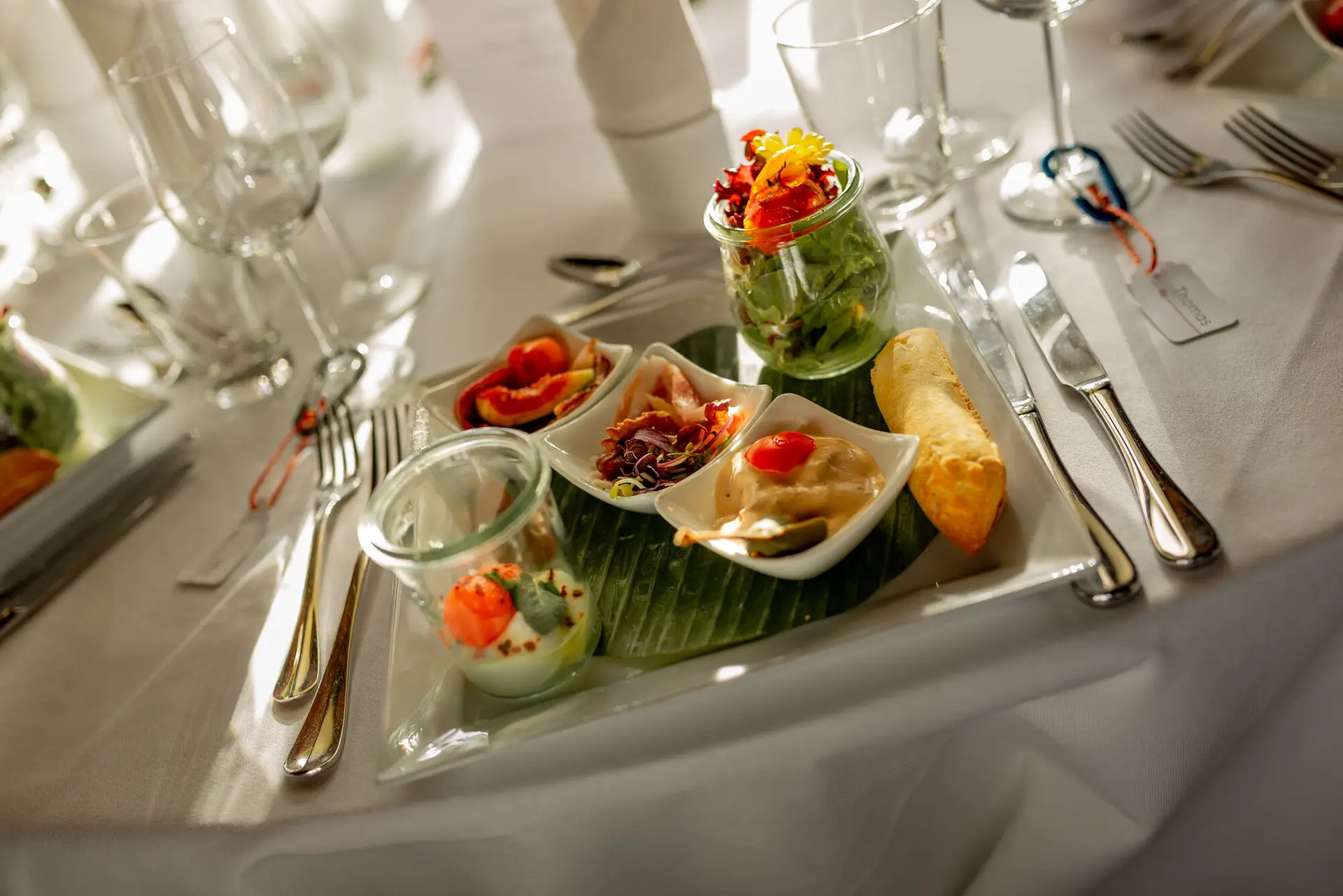 Tablett mit kleinen Vorspeisen – Salat, Garnelen, Dip und Brot – auf weißem Hochzeitstisch