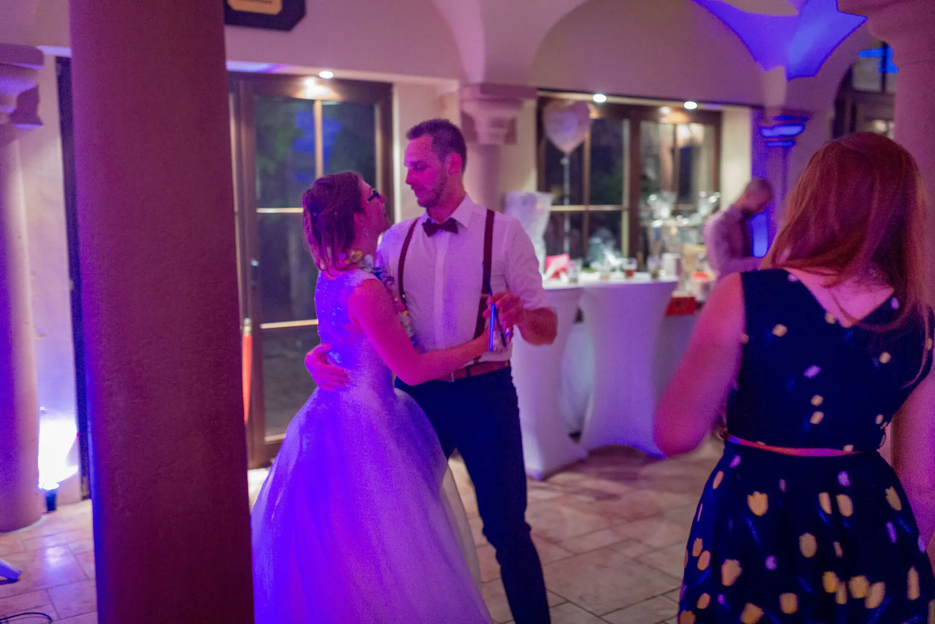 Bräutigam küsst seine Braut innig beim Tanz unter blauem Scheinwerferlicht auf der Tanzfläche