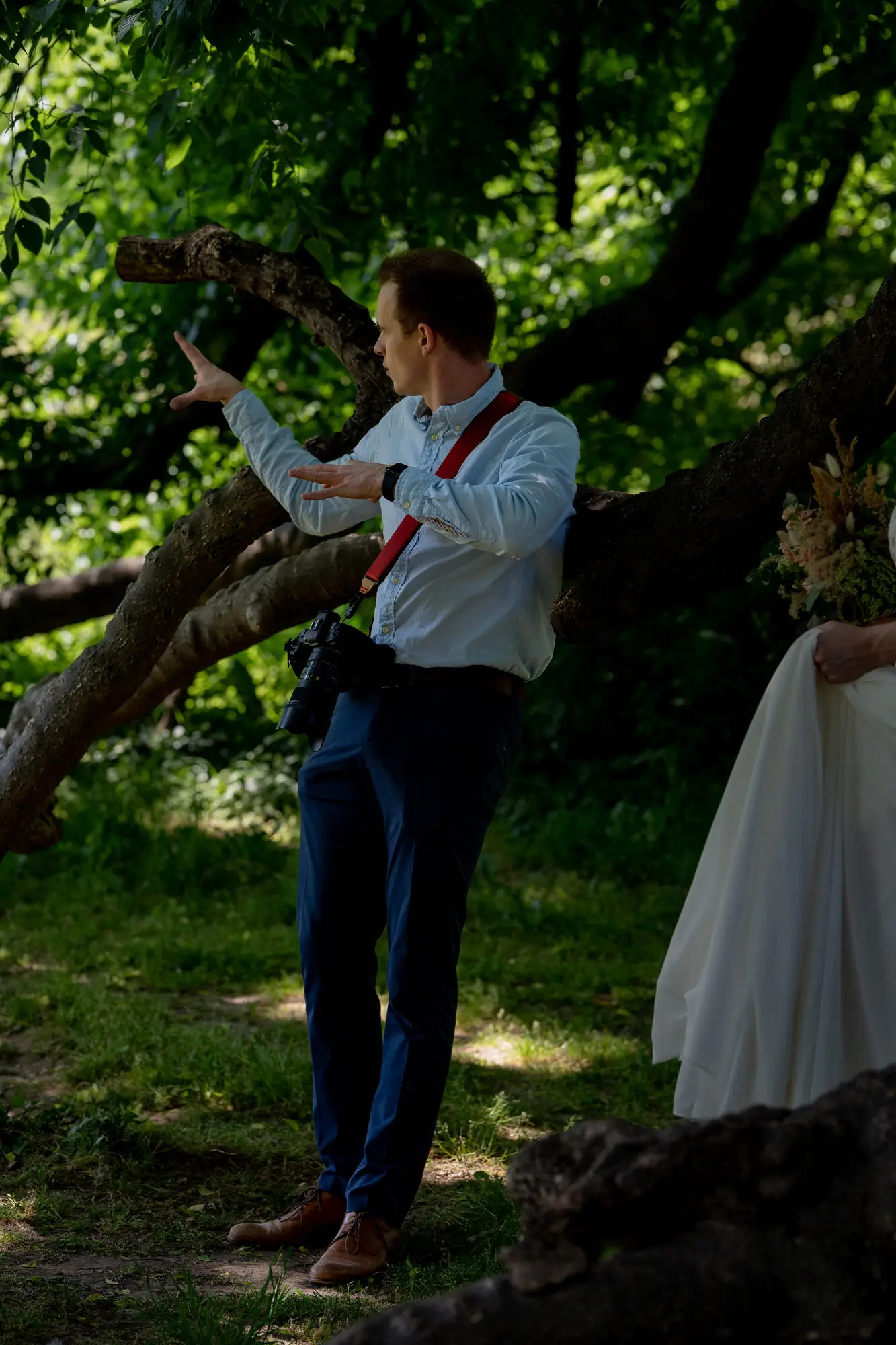 Behind the Scenes: Fotograf bei der Arbeit mit der Braut unter den Bäumen