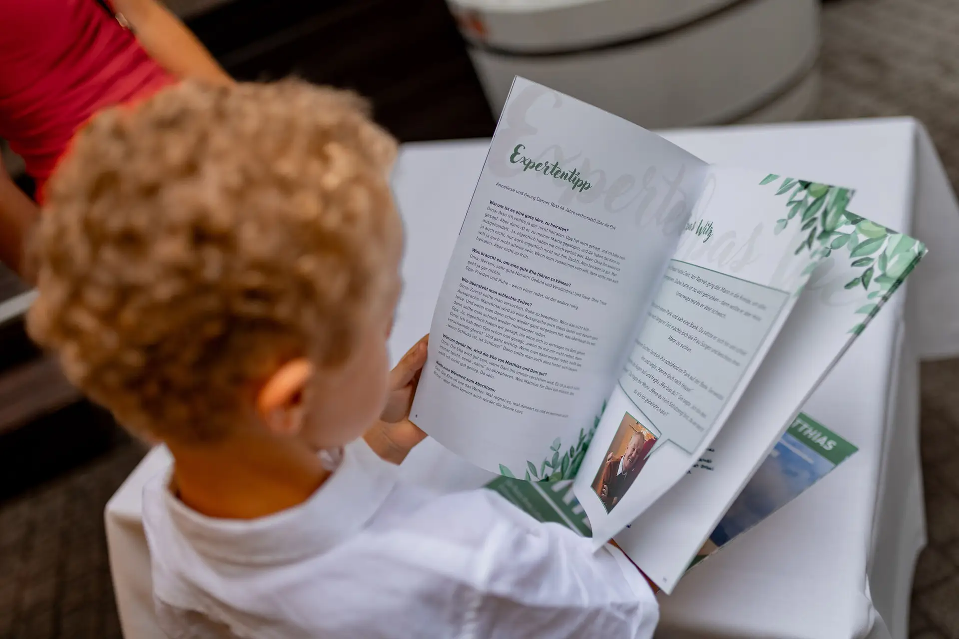 Kind liest aufmerksam im Hochzeitsheft bei der Feier in der Cantina Majolika