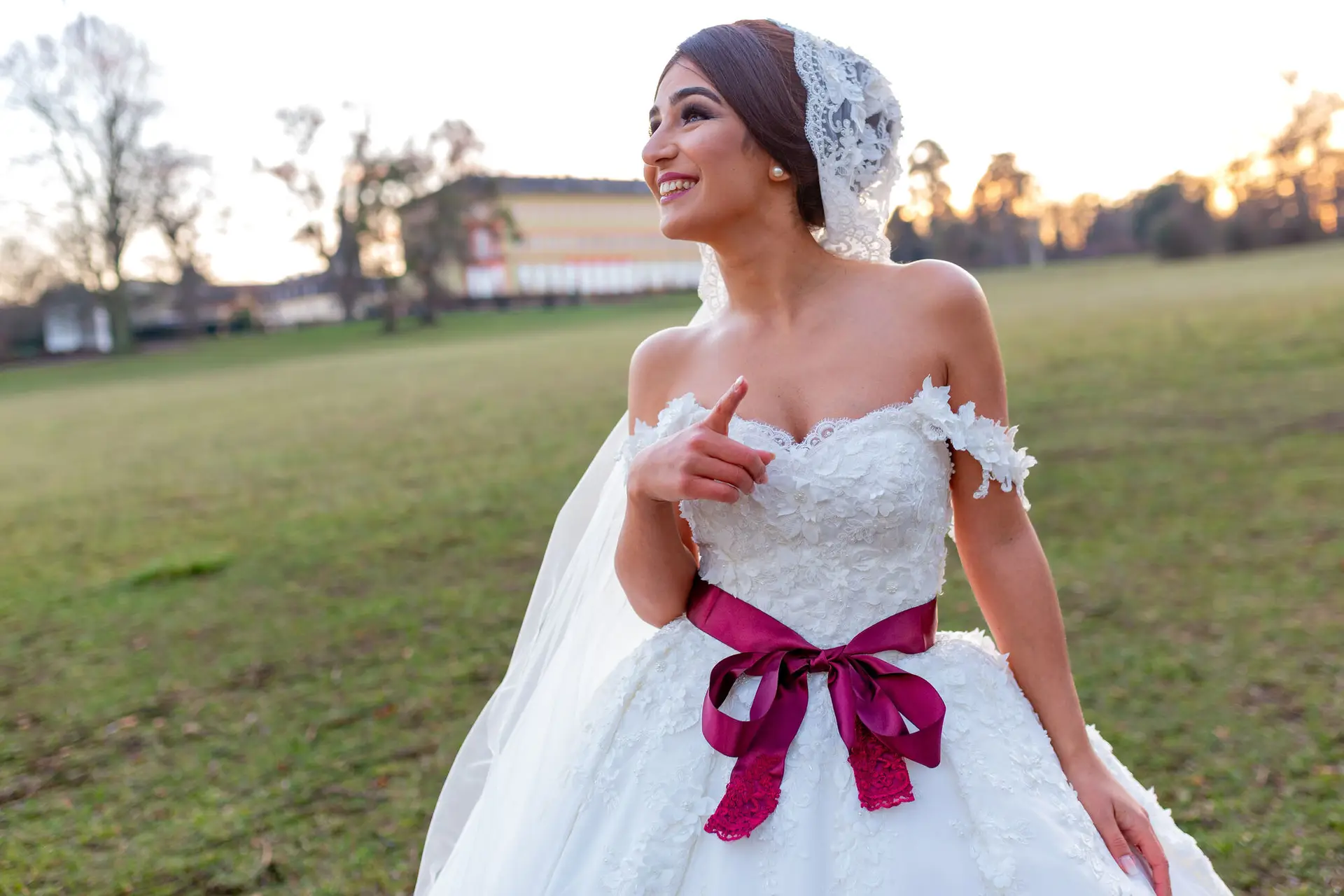 Braut im schulterfreien weißen Hochzeitskleid mit magentafarbenem Satinband, Detailaufnahme