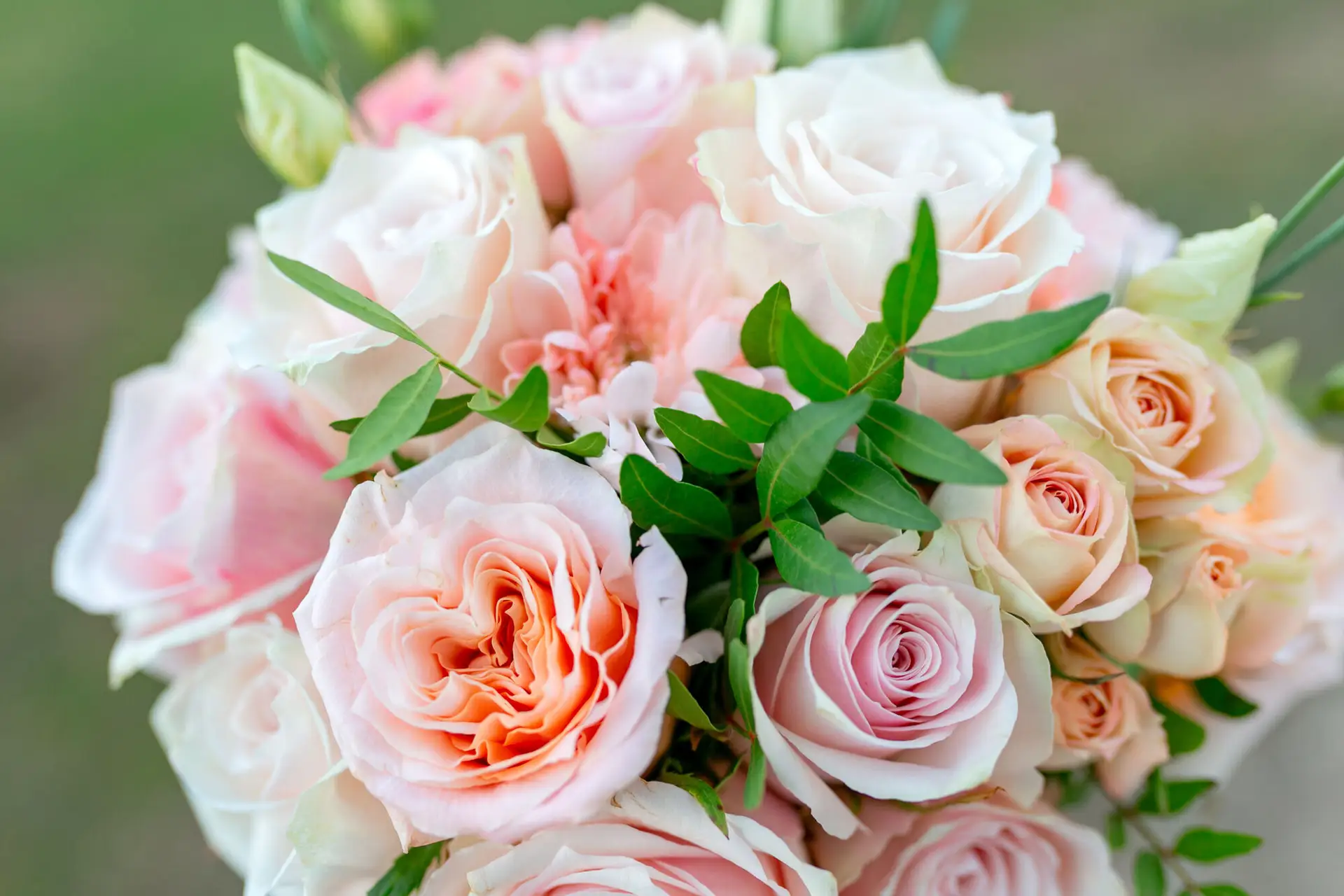 Runder Brautstrauß aus rosafarbenen und cremefarbenen Rosen, Detailaufnahme auf der Wiese