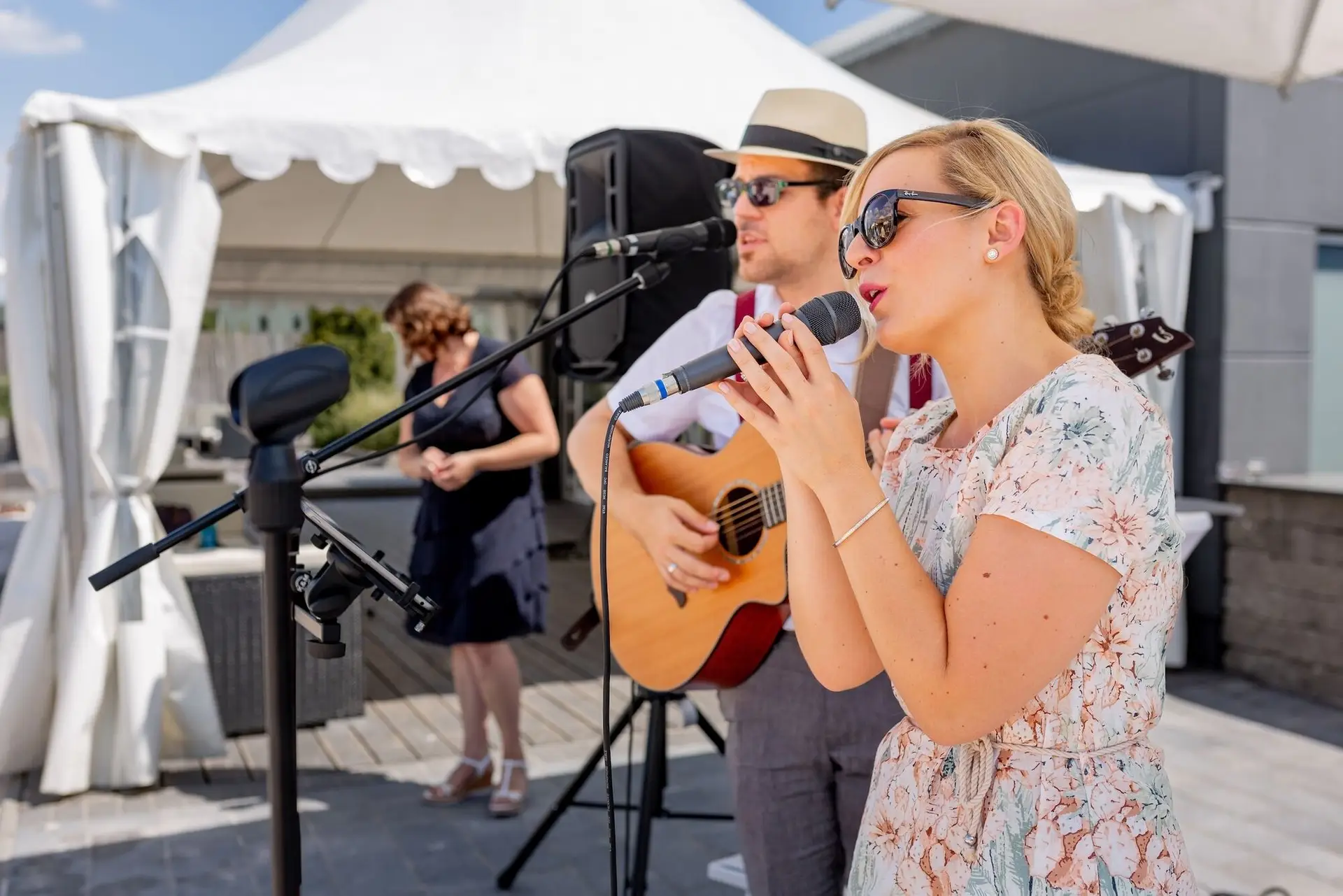 Live-Band spielt beim Hochzeitsempfang, Sängerin mit Mikrofon und Gitarrist mit Strohhut und Brille