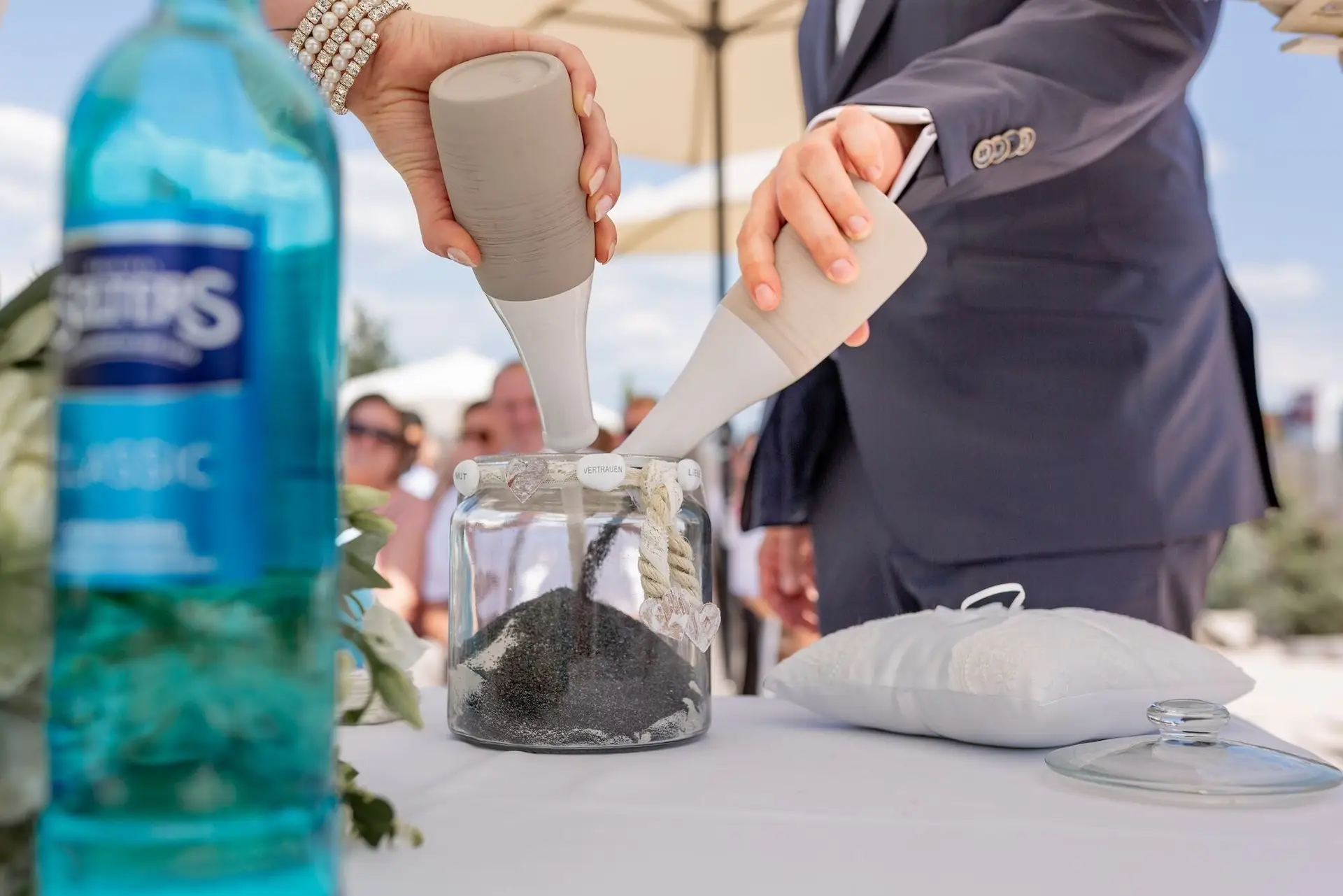 Vater der Braut vollzieht die Sandzeremonie und gießt Sand in eine Glasvase mit Anker-Symbol