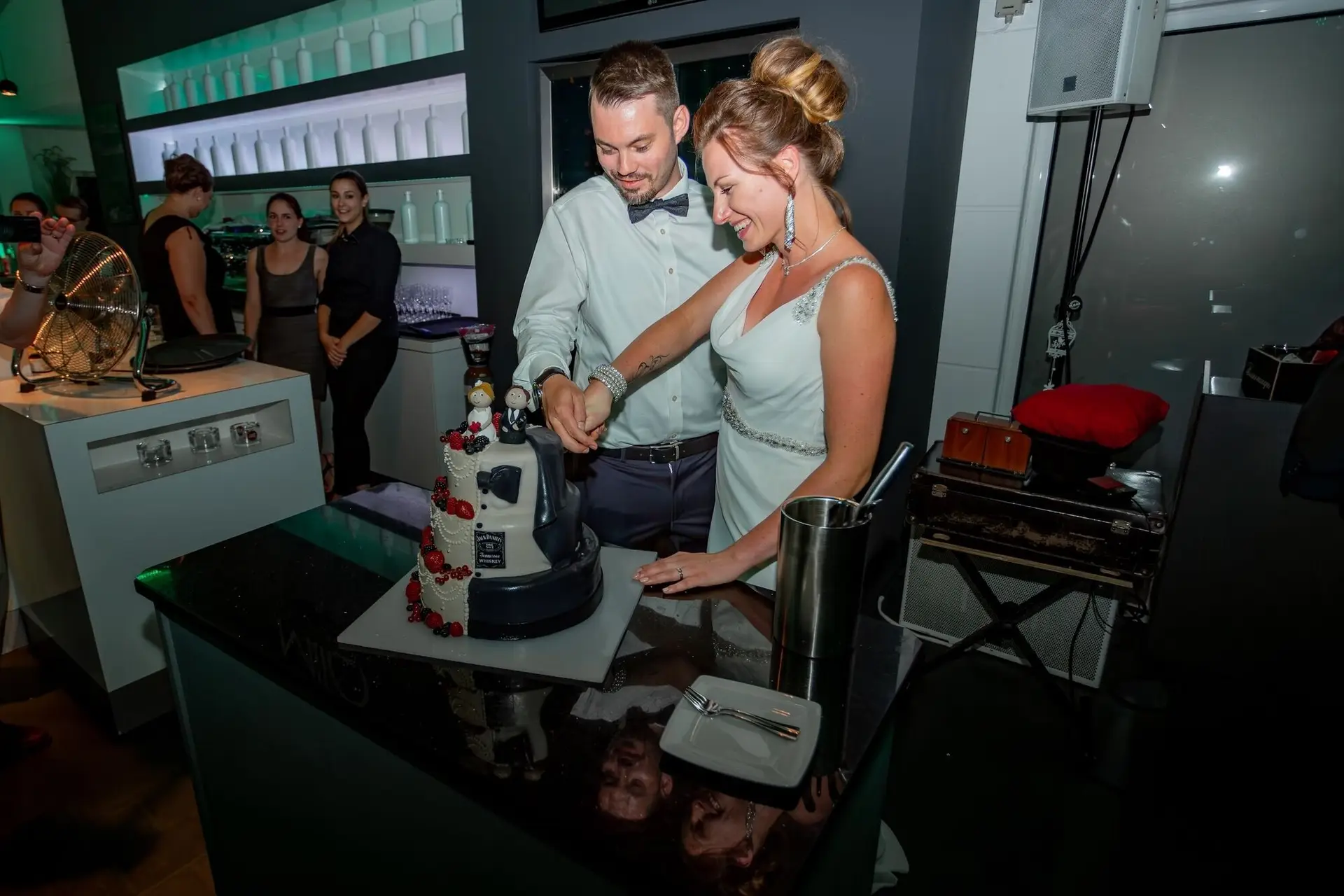 Brautpaar schneidet gemeinsam die außergewöhnliche Hochzeitstorte mit Jack-Daniel's-Motiv an