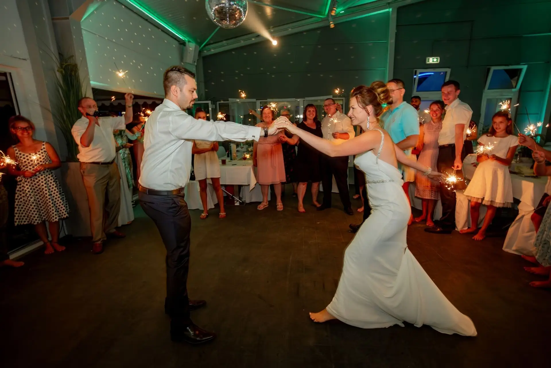 Bräutigam fängt seine tanzende Braut in den Armen, Wunderkerzen funkeln strahlend um sie herum