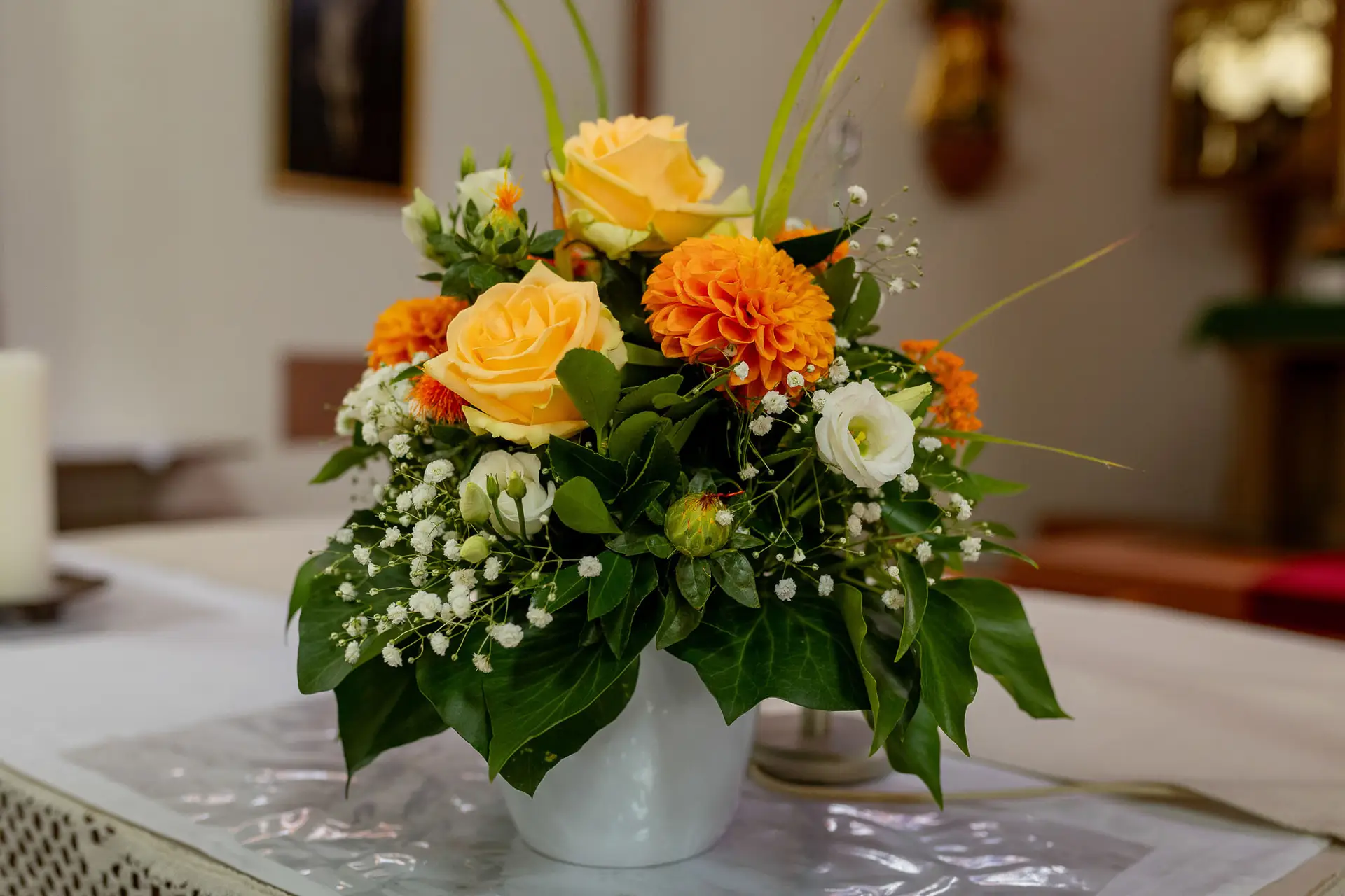 Blumenarrangement mit gelben Rosen und orangefarbenen Dahlien auf dem Tisch in der Kirche