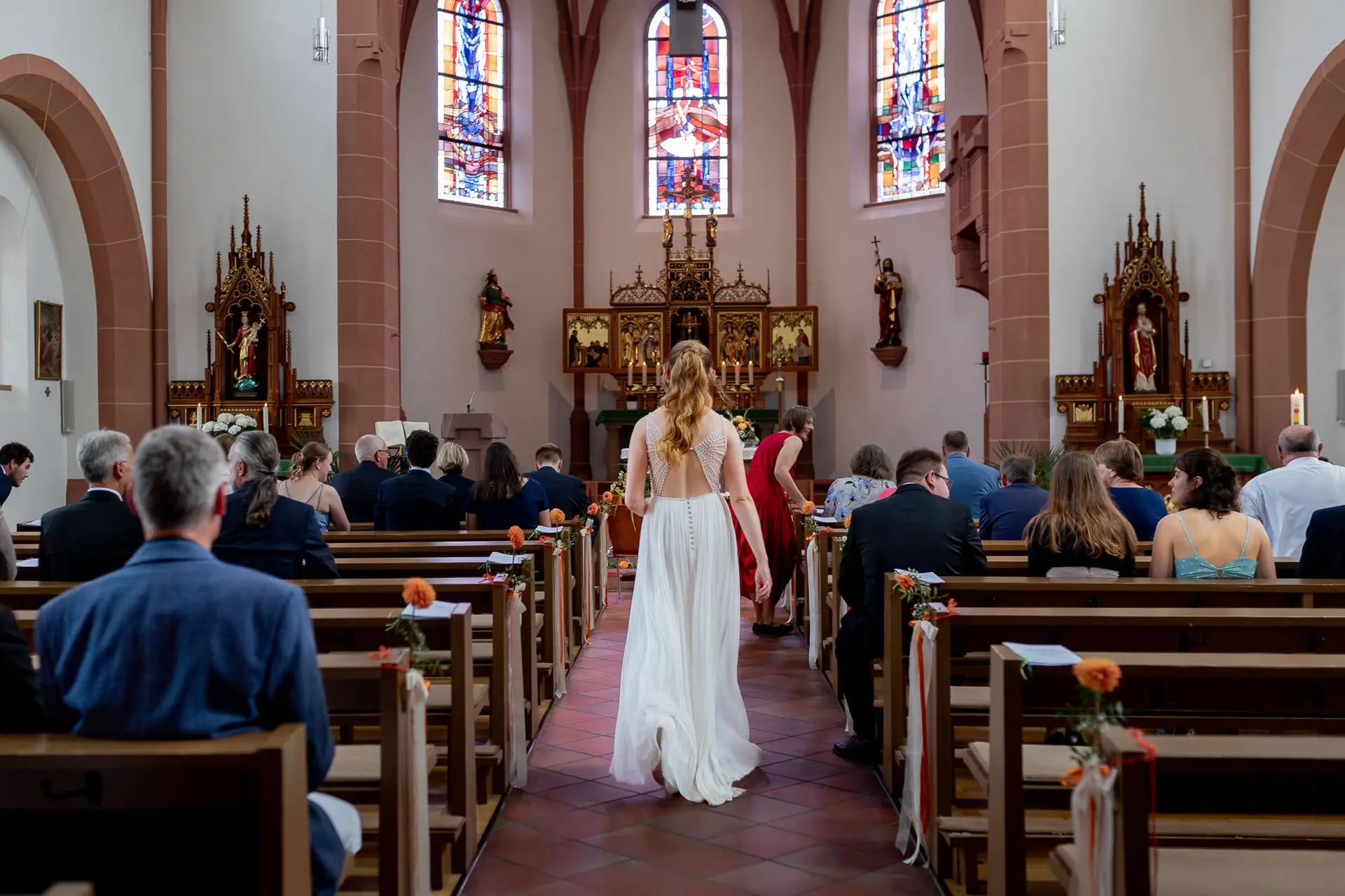Braut geht den Kirchenmittelgang zur Trauung in St. Johannes der Täufer Bad Münster entlang