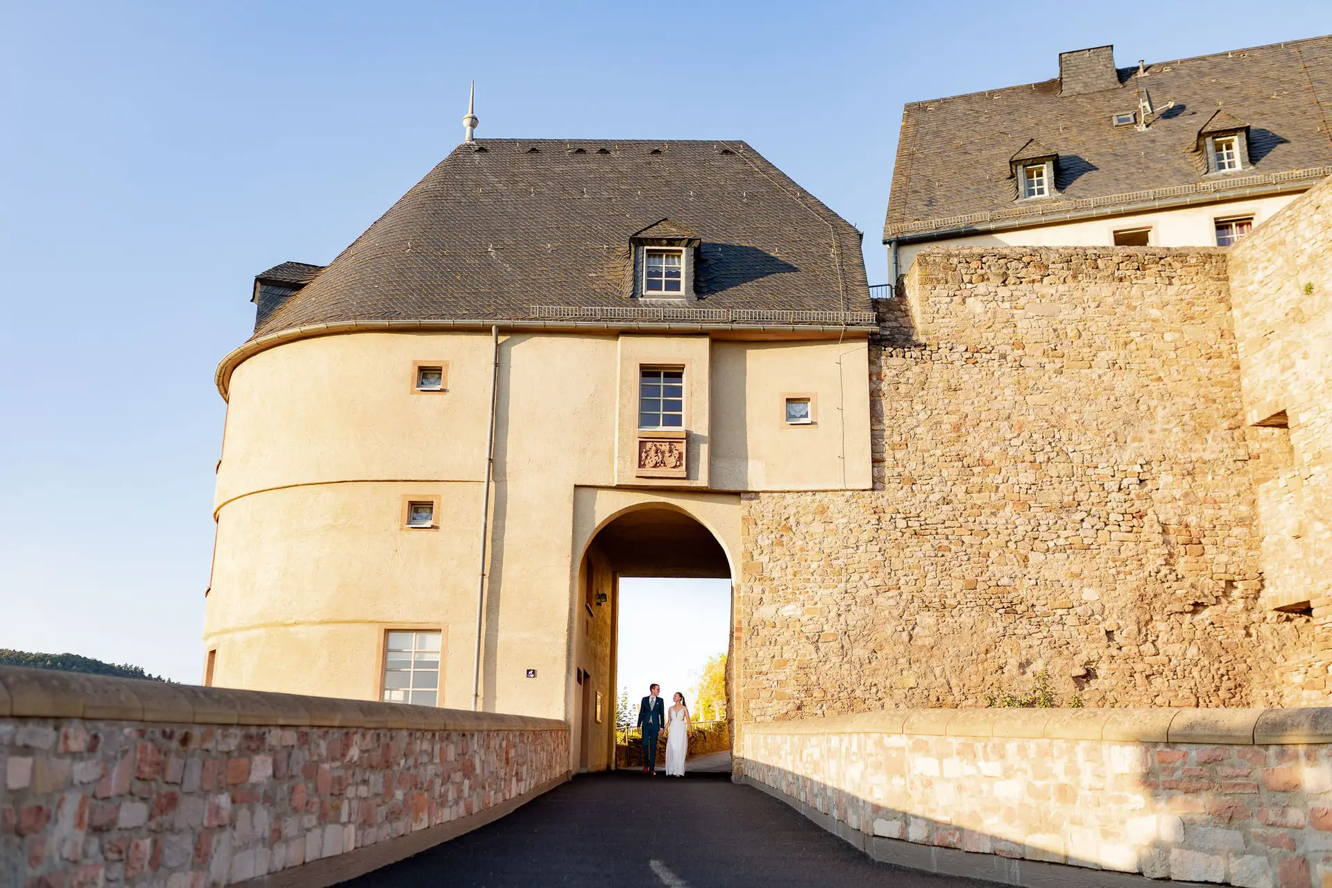 Brautpaar vor dem historischen Burgtor der Burg Ebernburg im goldenen Abendlicht
