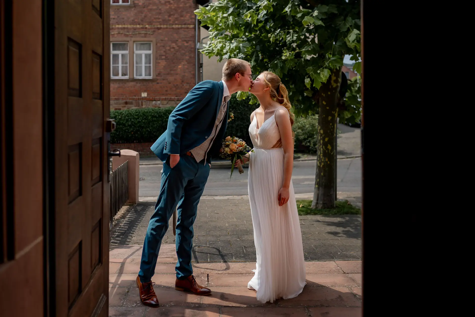 Bräutigam küsst seine Braut vor dem historischen Kirchengebäude in Bad Münster am Stein