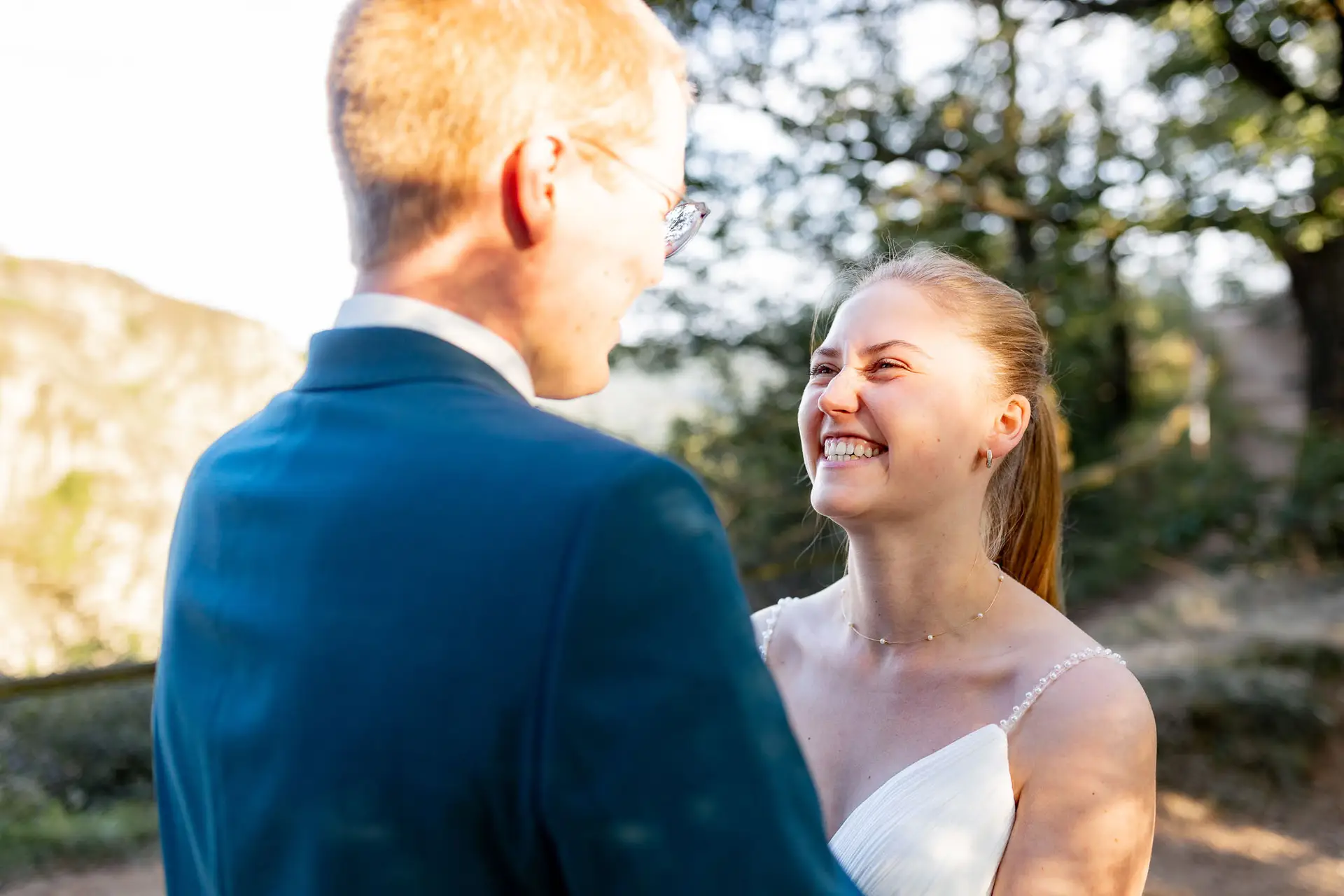 Braut und Bräutigam lächeln sich unter Bäumen an beim Brautpaarshooting an der Burg Ebernburg