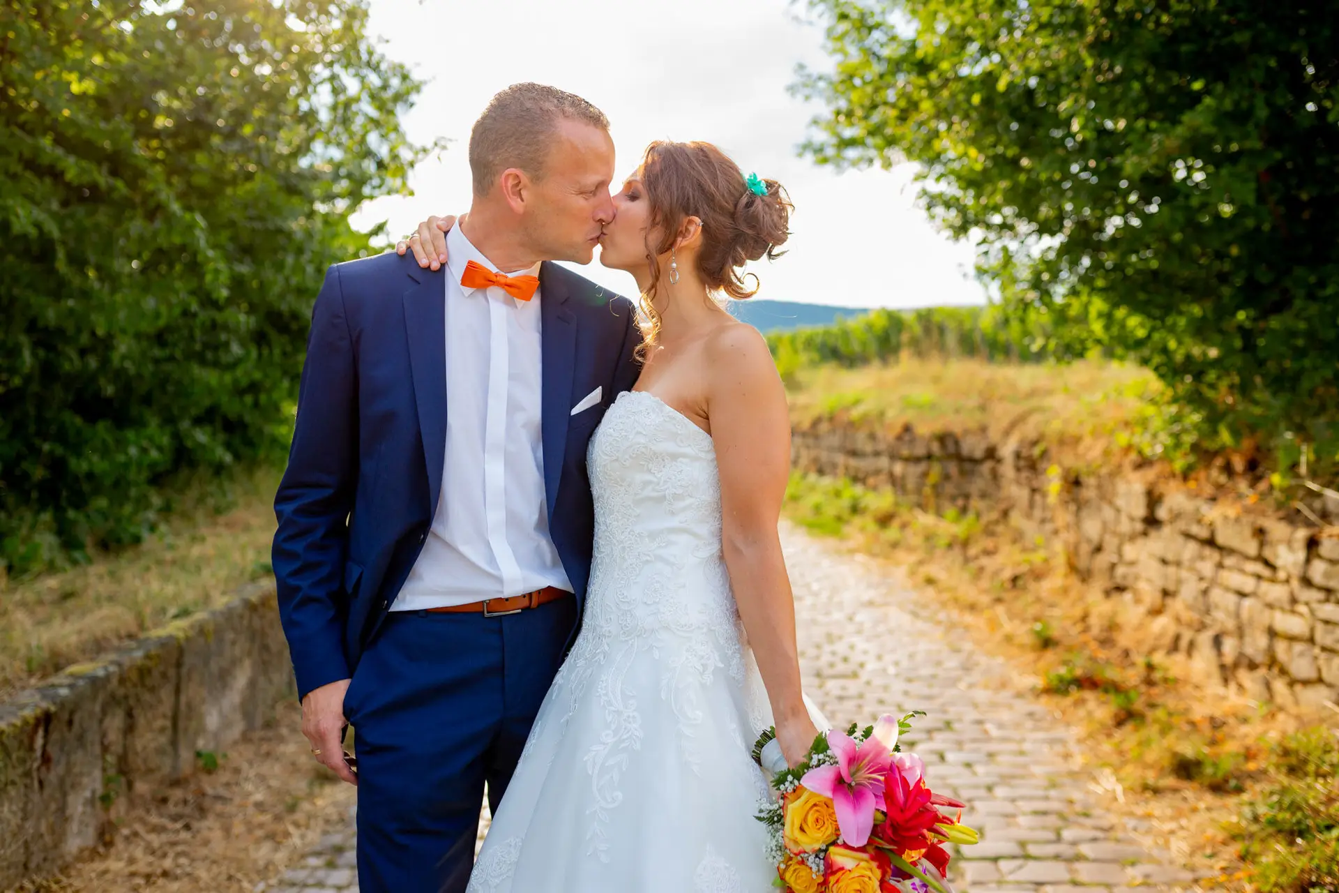 Jennifer und Gregor küssen sich vor einer Steinmauer in Deidesheim – goldene Stunde