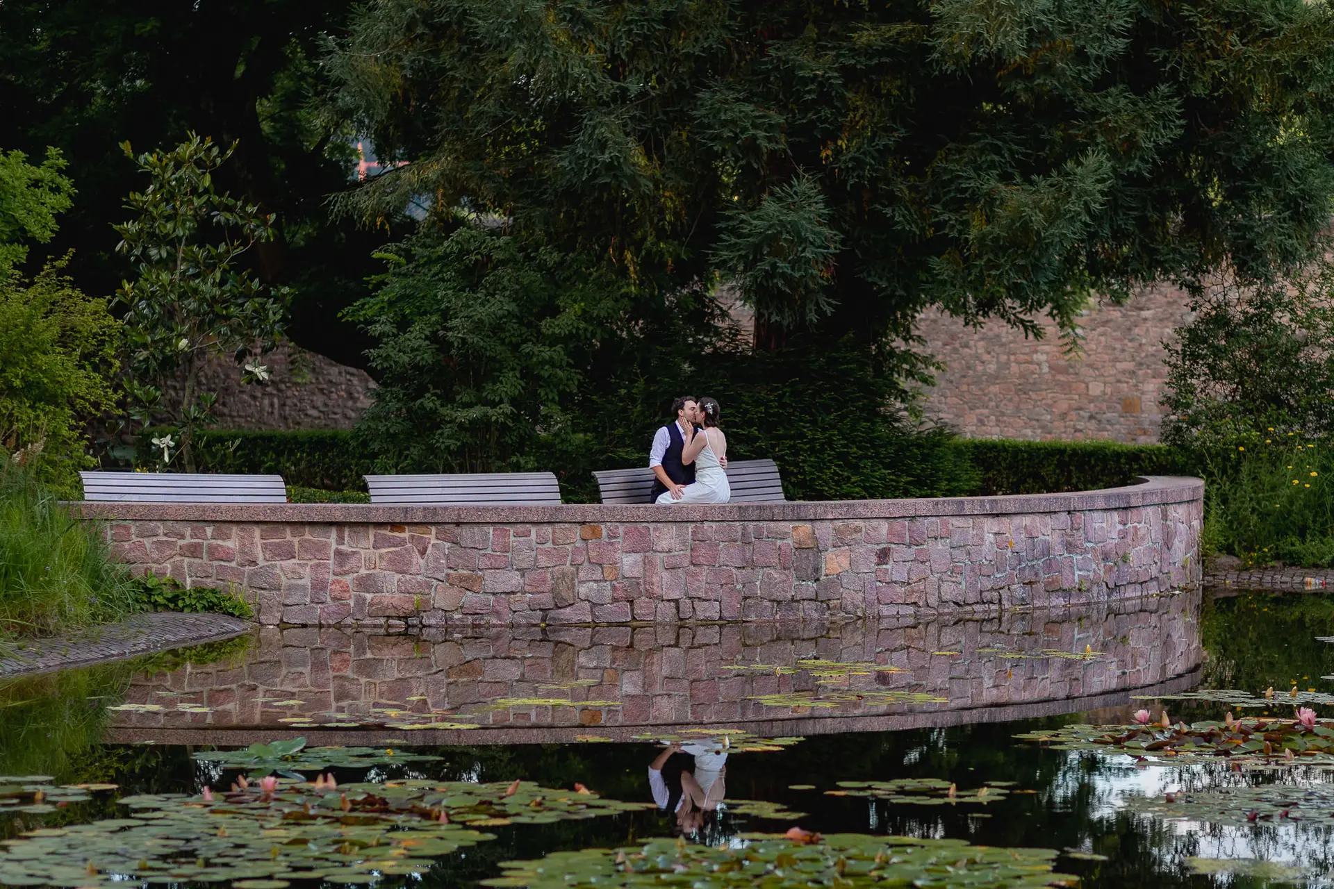 Brautpaar sitzt auf einer Brücke im Schlosspark Weinheim und blickt über den Teich im Dunkeln