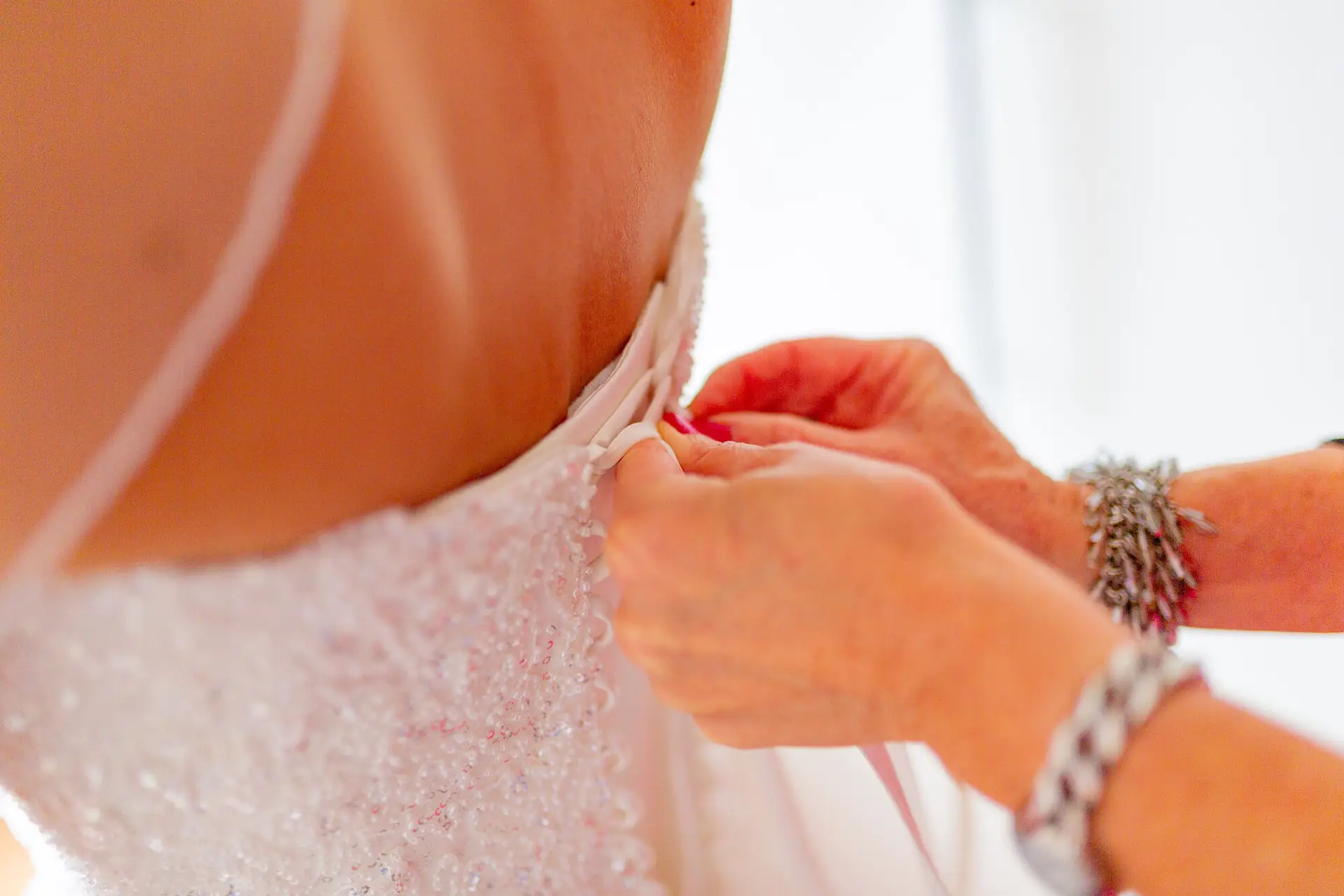 Nahaufnahme beim Schließen des Brautkleids am Rücken