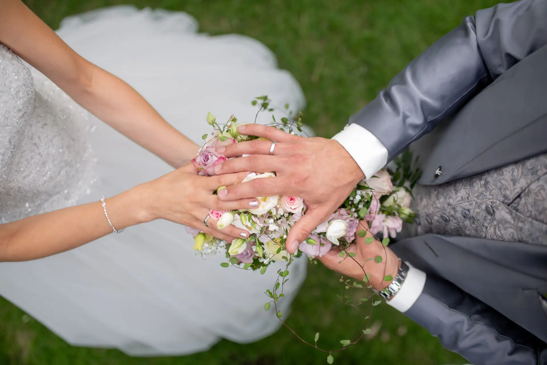 Brautpaar Hände mit Eheringen auf dem Brautstrauß, Draufsicht