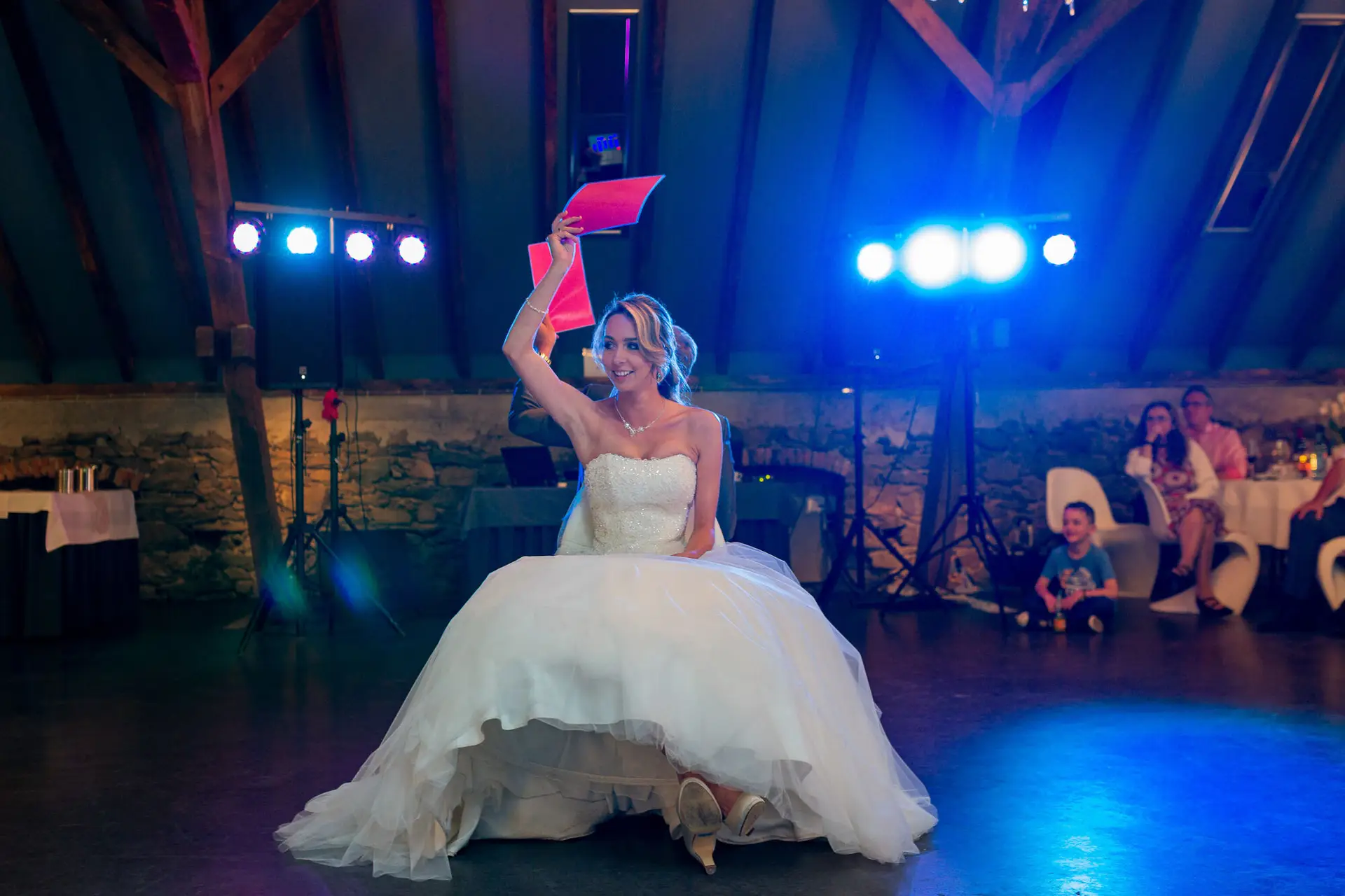Braut hebt lachend ein Hochzeitsmagazin auf der Tanzfläche im Hofgut Hohenstein