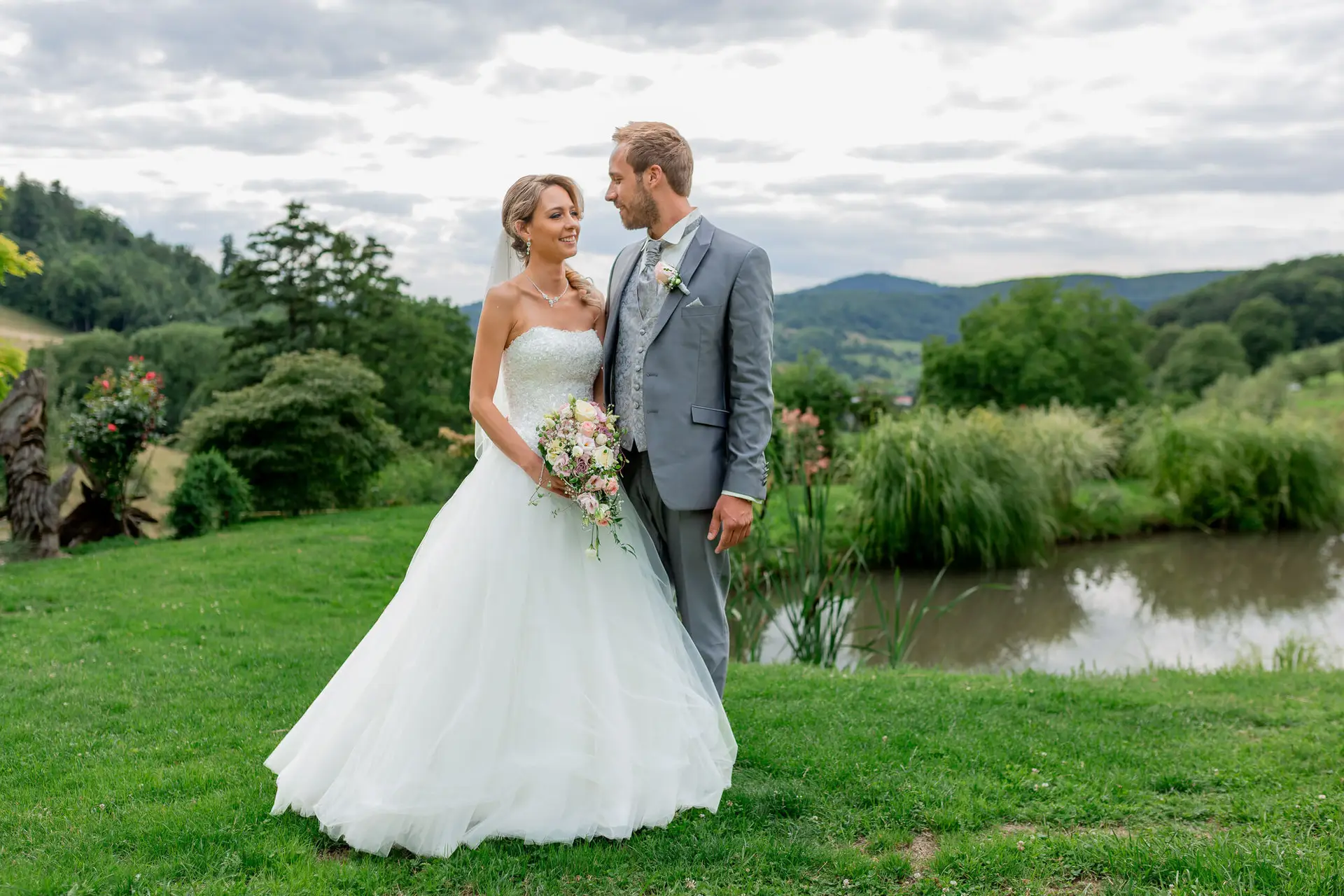 Brautpaar im Garten des Hofgut Hohenstein mit Teich und Bergpanorama