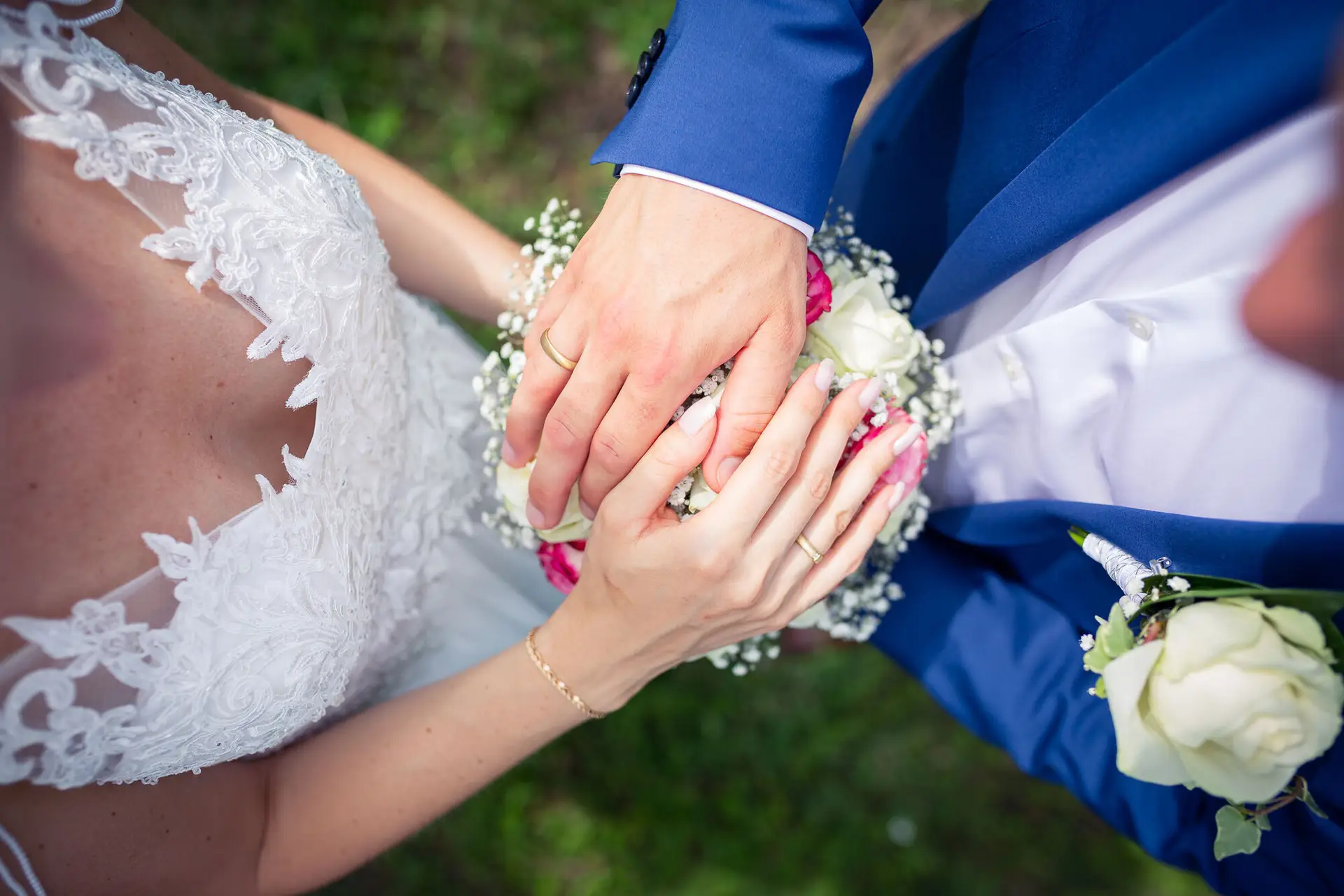 Detailaufnahme der Hände von Liane und Kevin mit Eheringen auf dem Brautstrauß