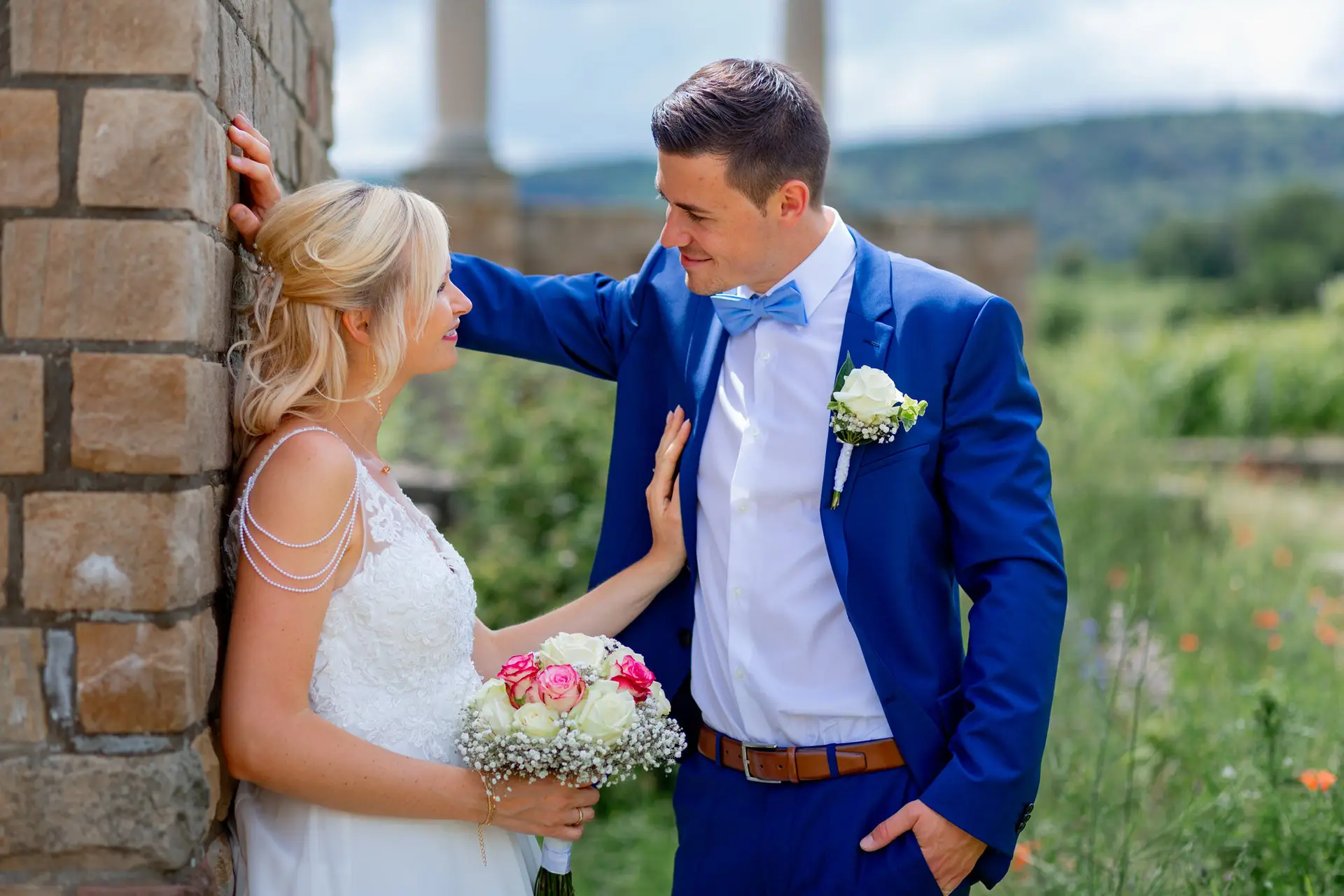 Liane und Kevin von hinten zwischen Weinreben mit Ring-Ballons – Brautpaarshooting in der Pfalz