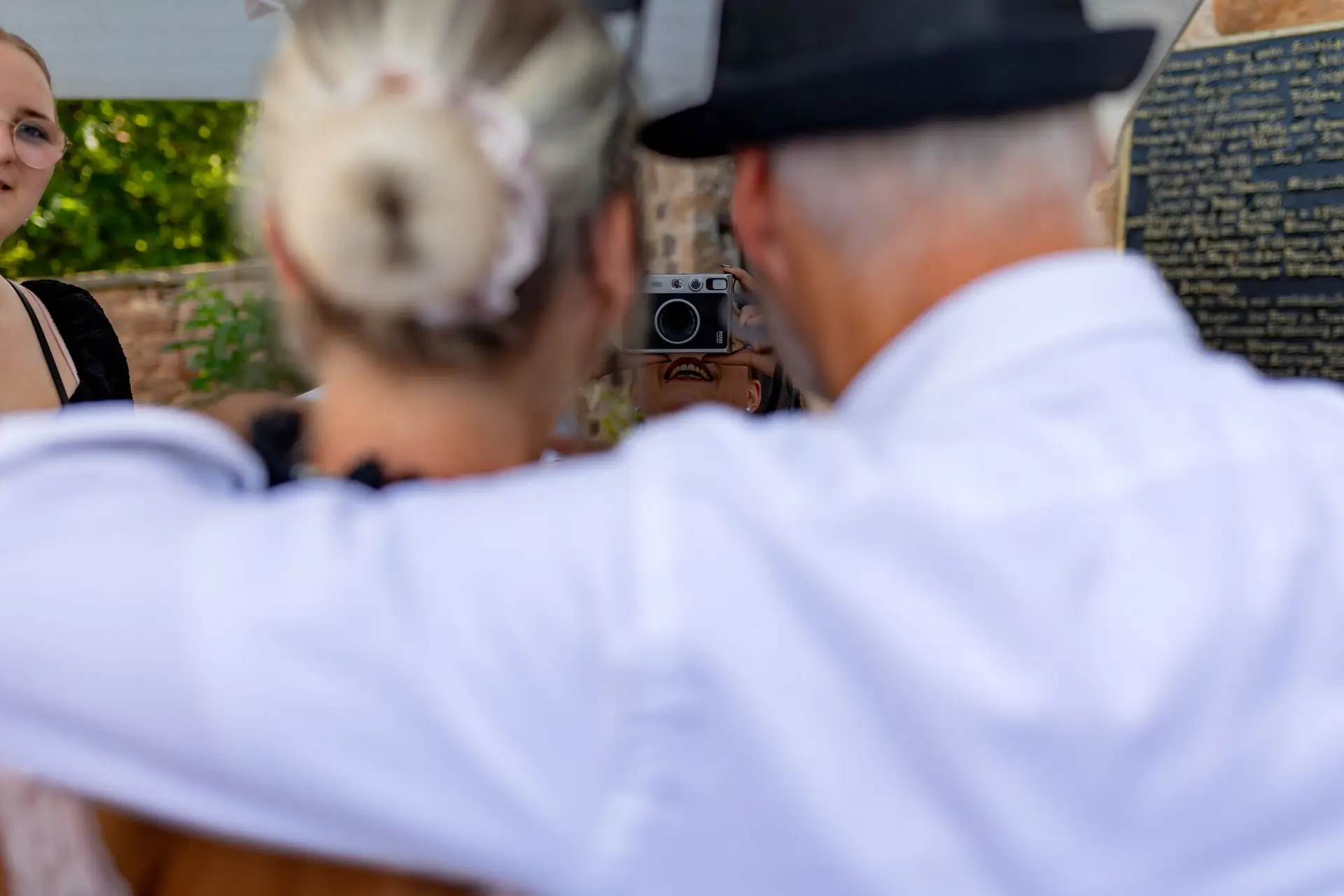 Gast mit Hut fotografiert mit alter Kamera auf der Hochzeitsfeier in der Burgschenke Neuleiningen