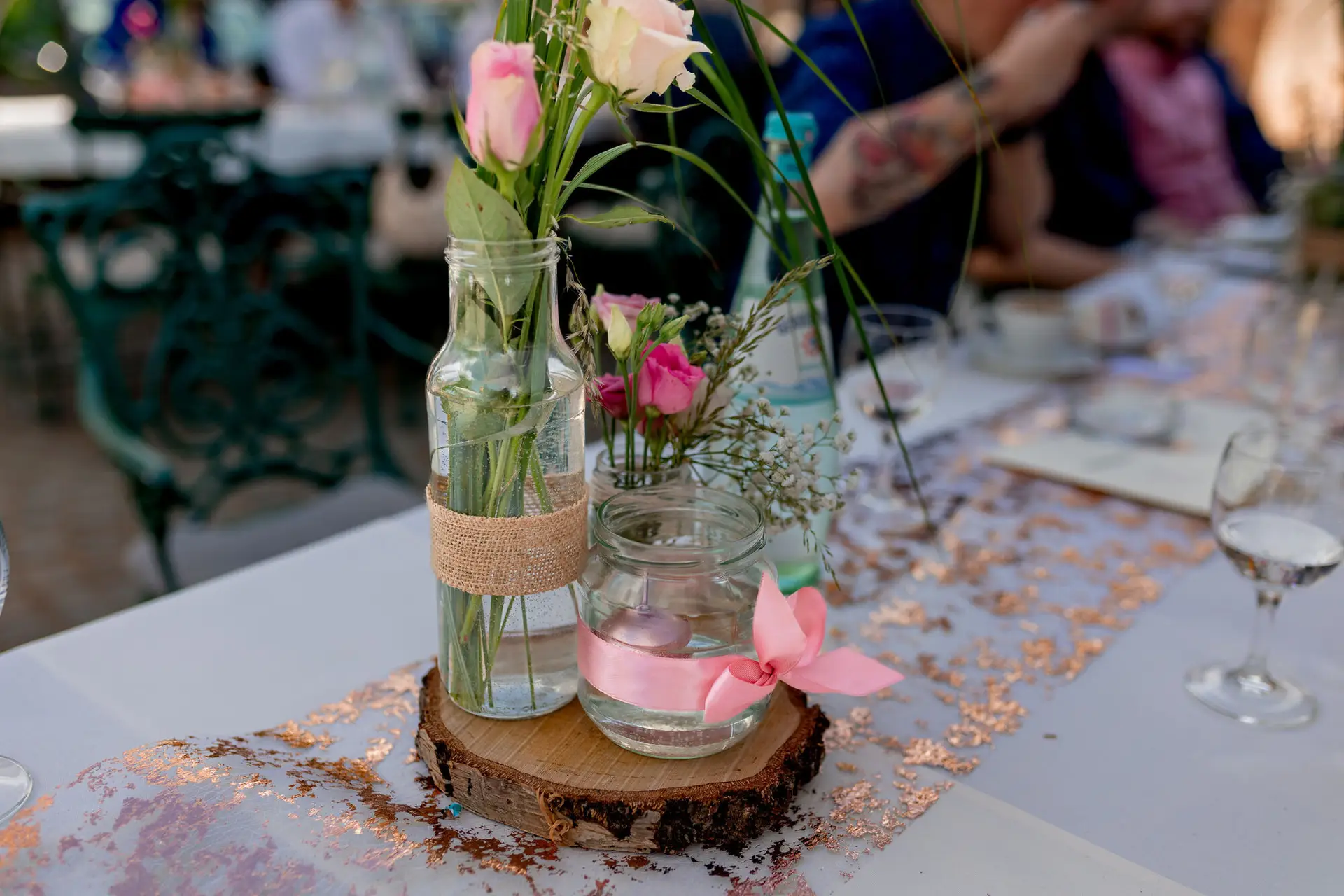 Tischdekoration mit rosa Rosen in Glasvasen auf Holzscheibe und rosa Schleife auf der Burgschenke Neuleiningen