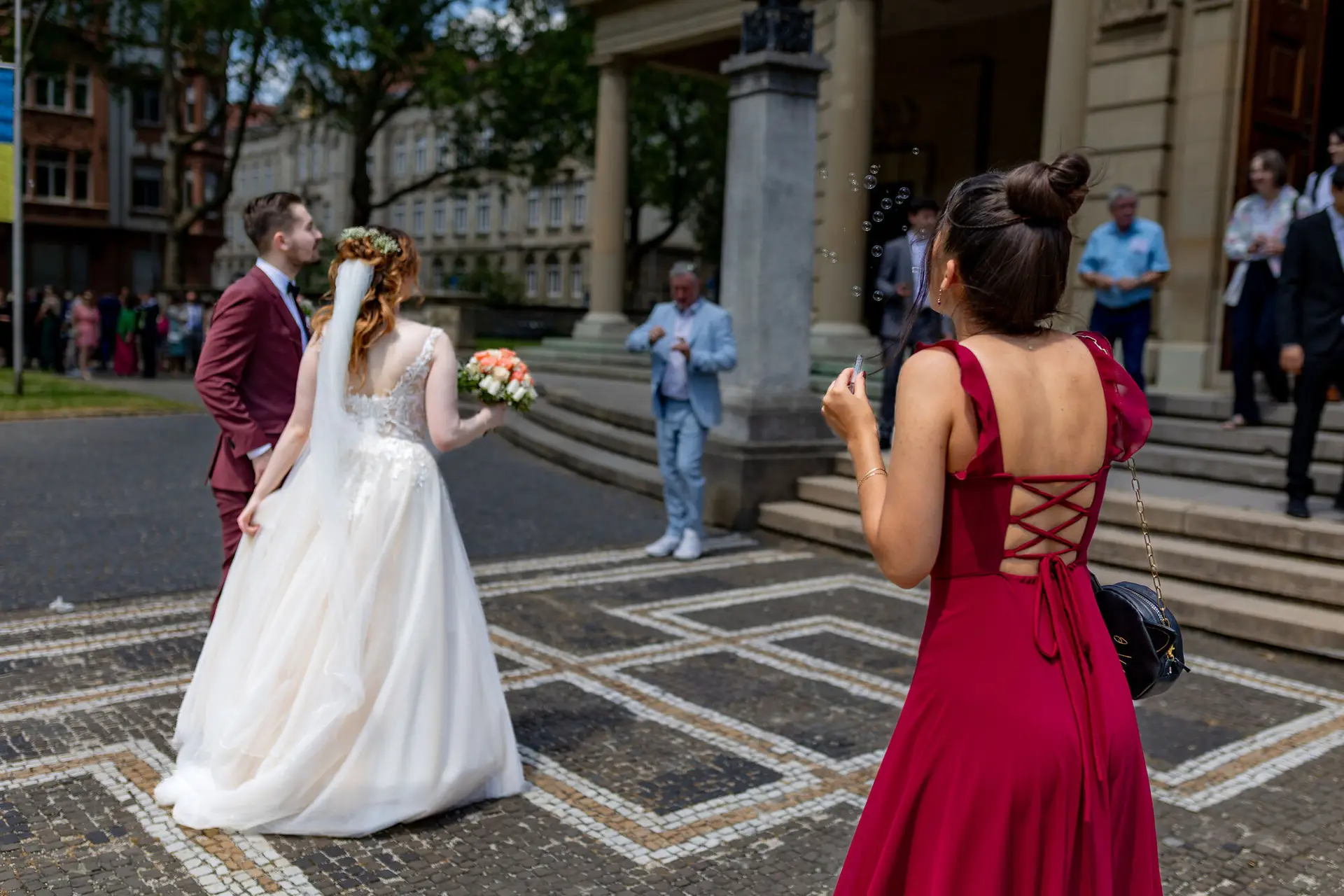 Brautpaar beim Auszug aus der Christuskirche, Gast im roten Kleid macht Seifenblasen