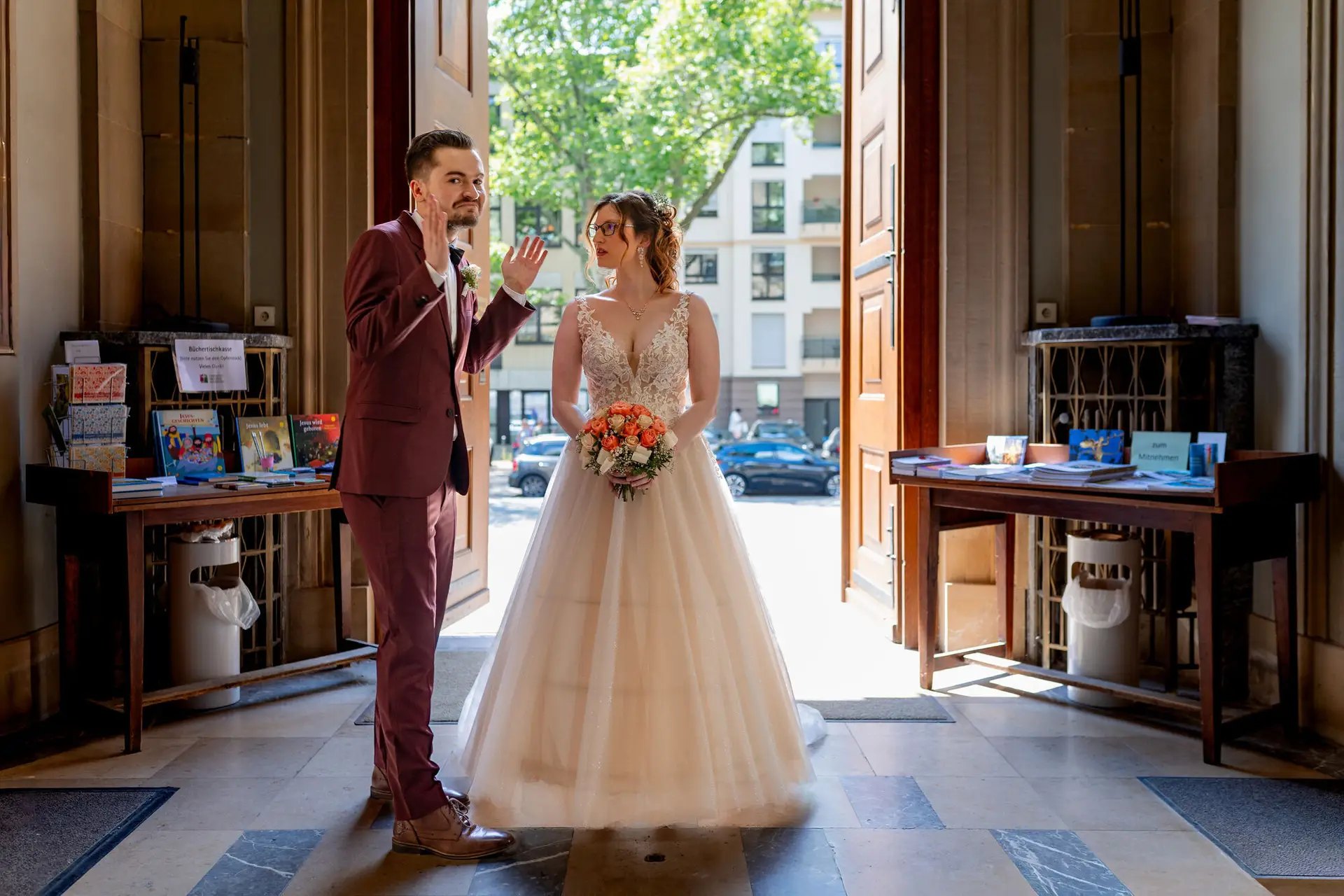Brautpaar im Eingang der Christuskirche Mannheim, Bräutigam winkt, Gegenlicht von draußen