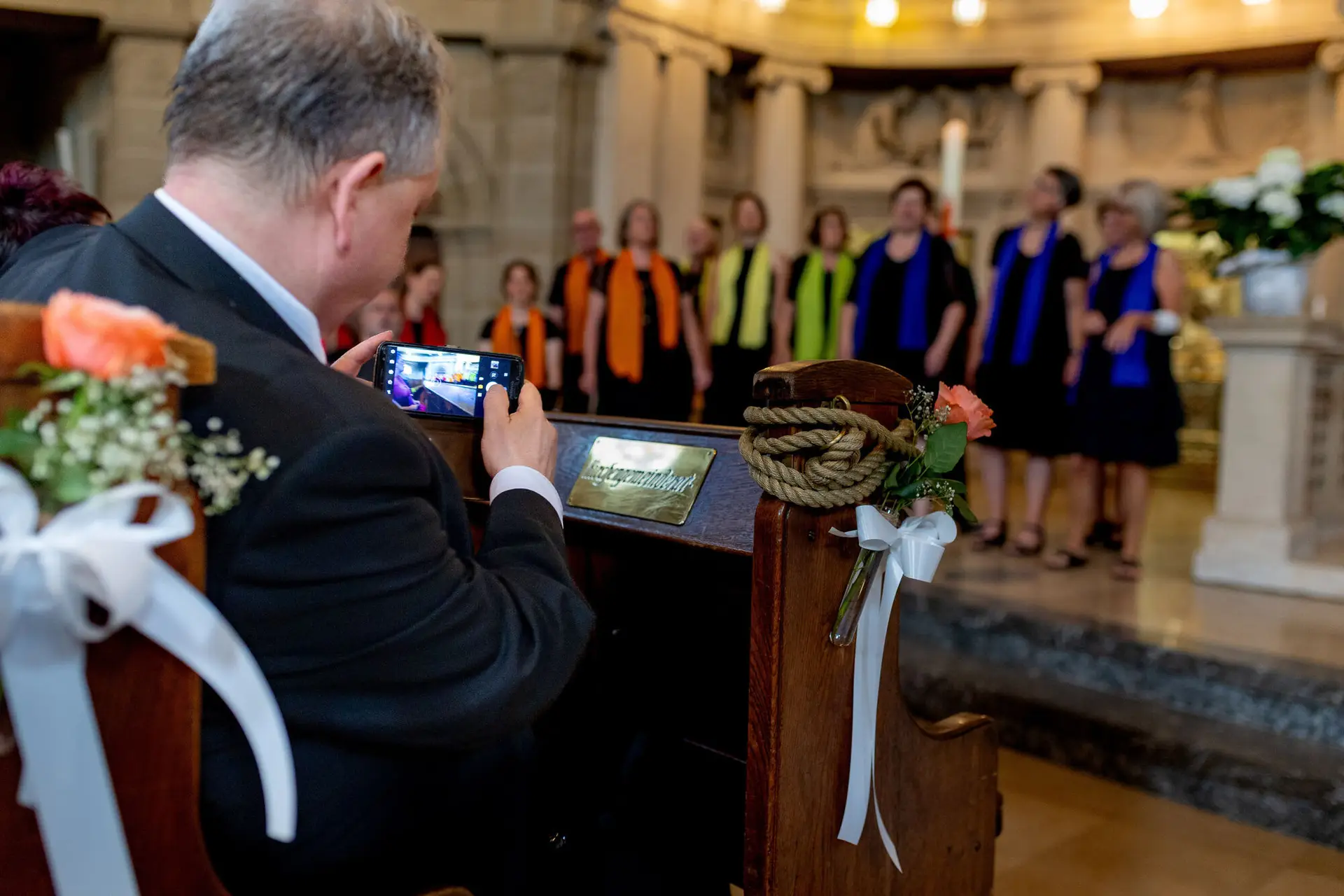 Hochzeitsgast fotografiert die Zeremonie mit Smartphone im prachtvollen Kirchenschiff