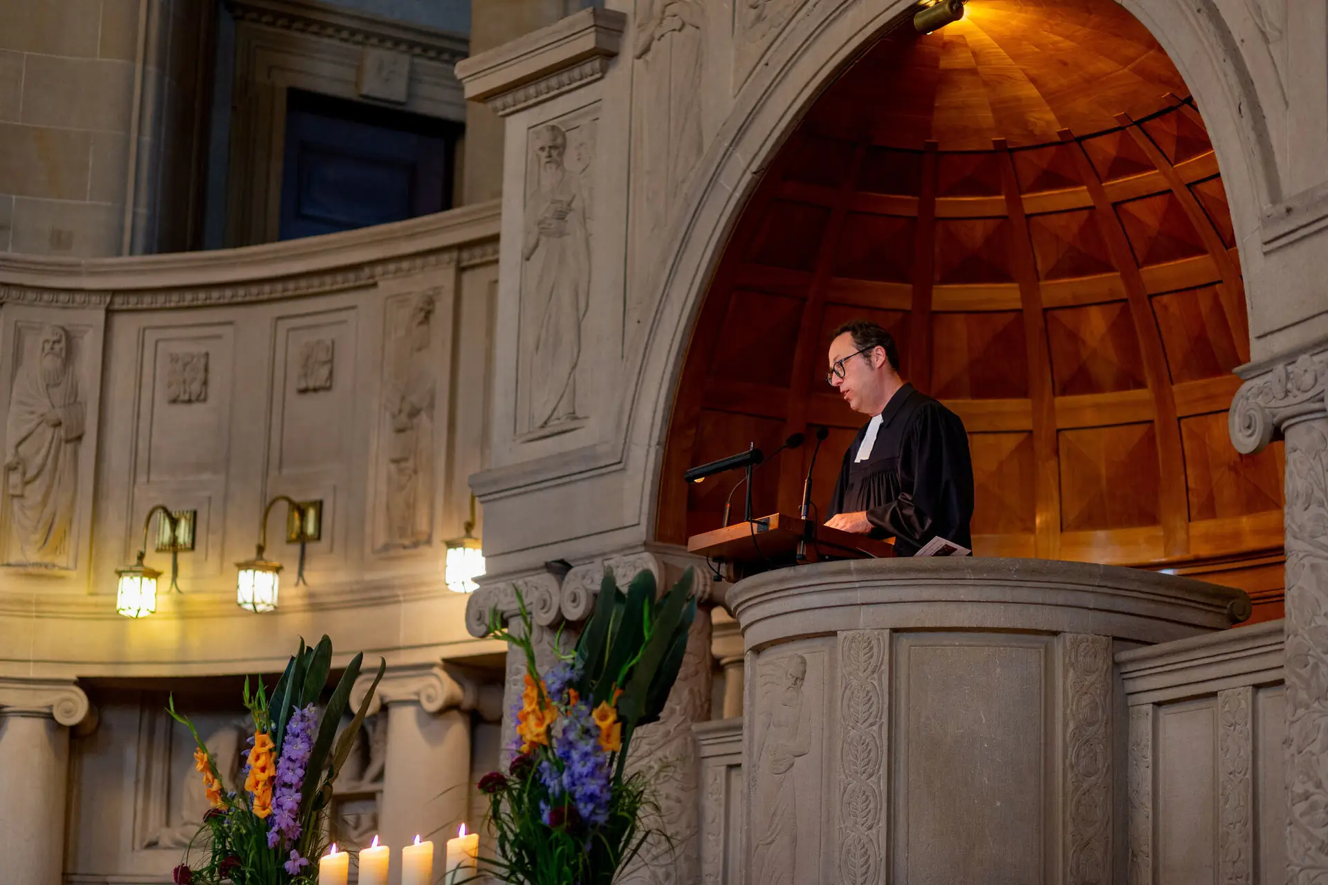 Priester hält die kirchliche Trauzeremonie im gotischen Kirchenschiff mit Blumen und Kerzen am Altar