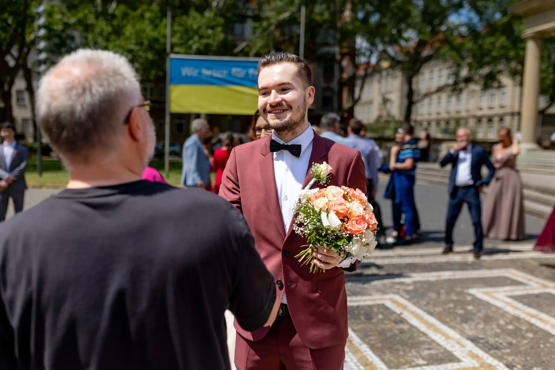 Bräutigam überreicht einen roten Blumenstrauß vor dem belebten Stadtbild Mannheims nach der Trauung