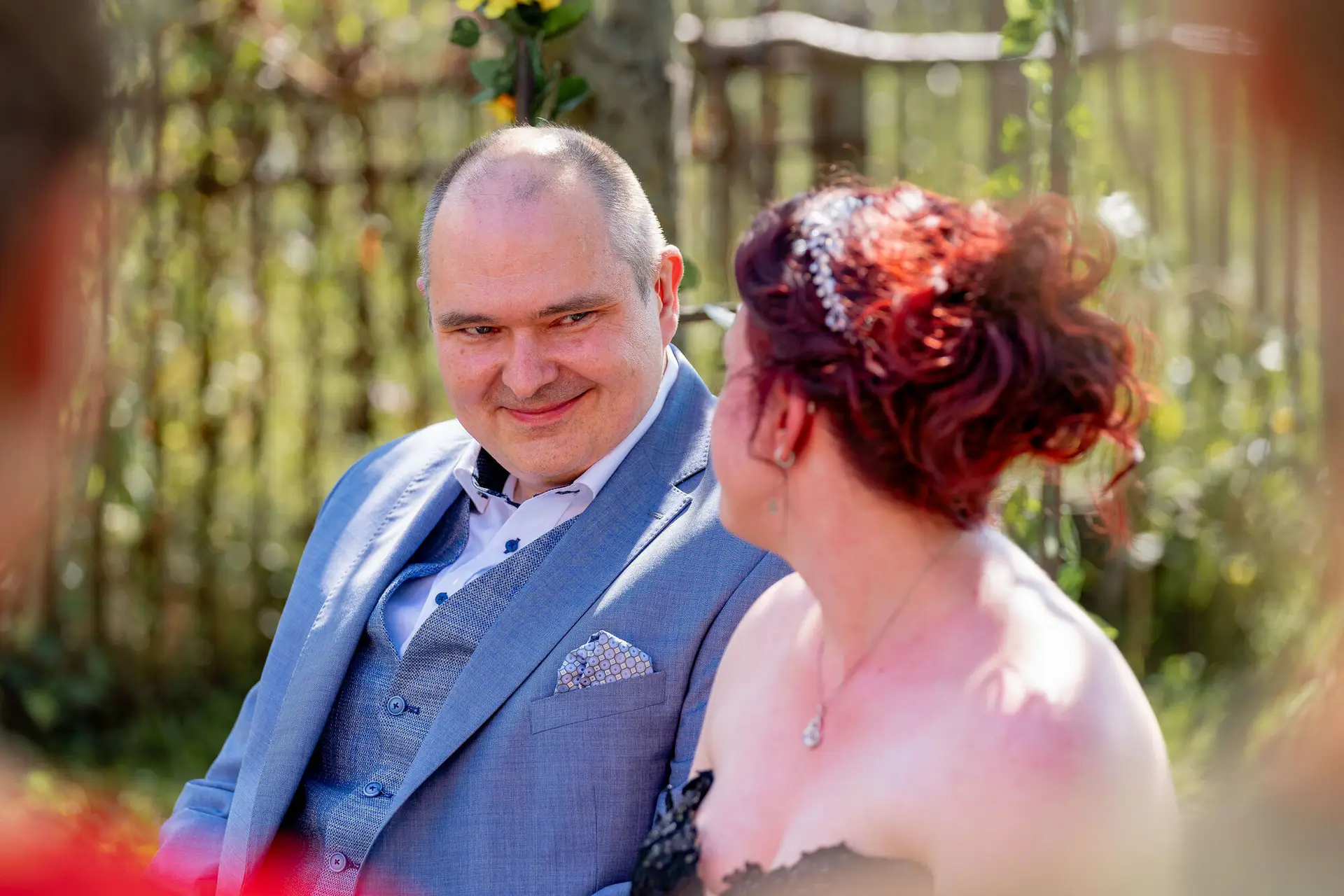 Bräutigam blickt Braut liebevoll an während der freien Trauung im Garten