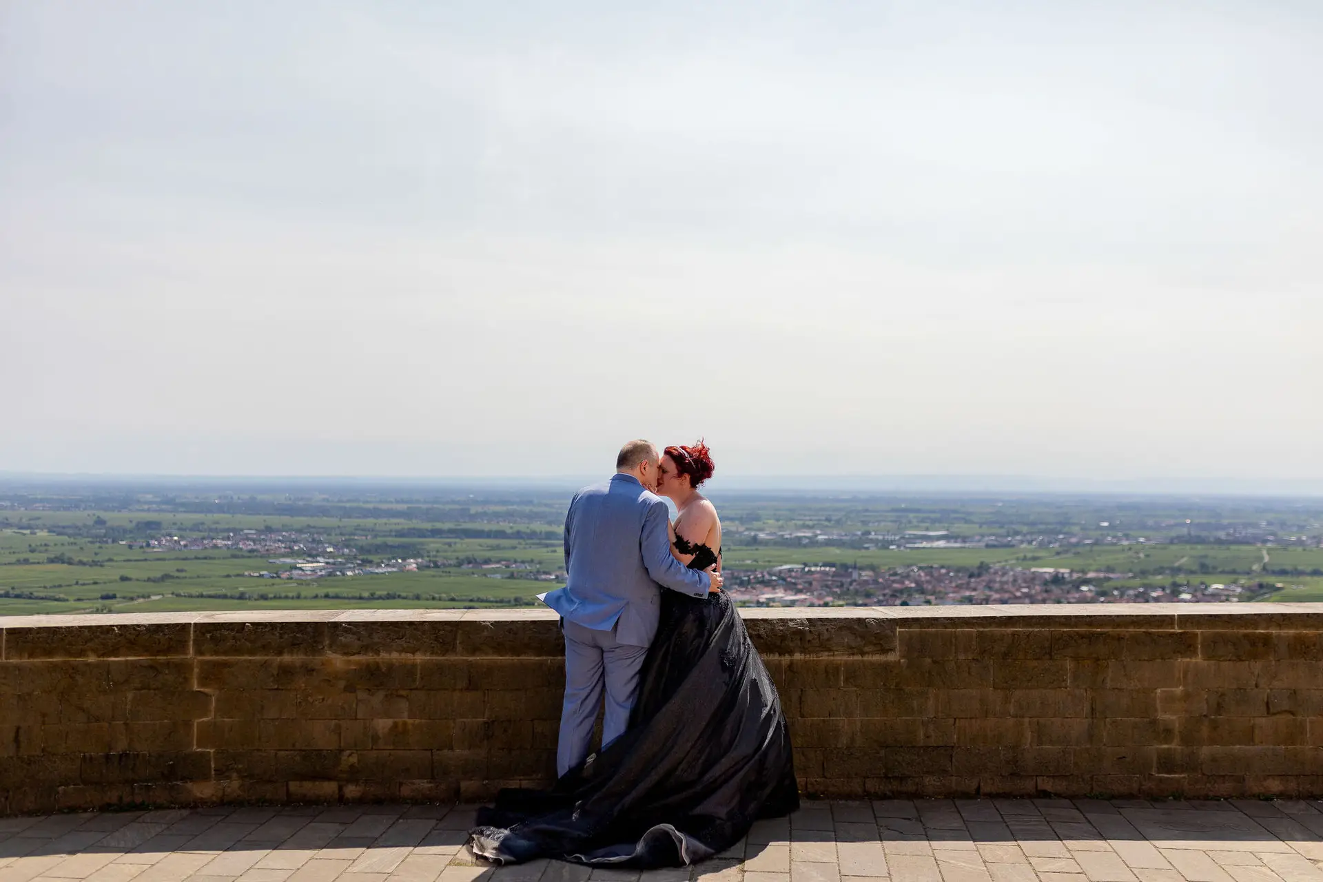 Brautpaar küsst sich auf Schlossterrasse mit weitem Panoramablick über die pfälzische Rheinebene