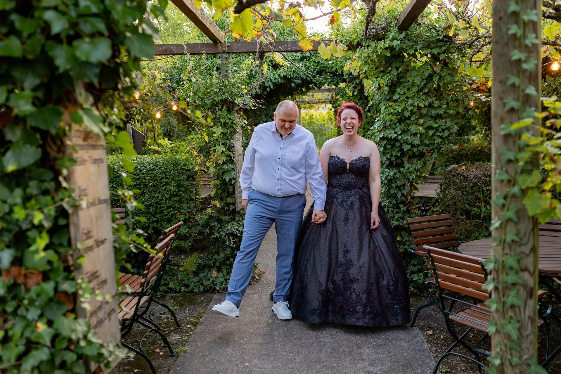 Brautpaar geht lachend durch den Laubengang von Kellers Keller